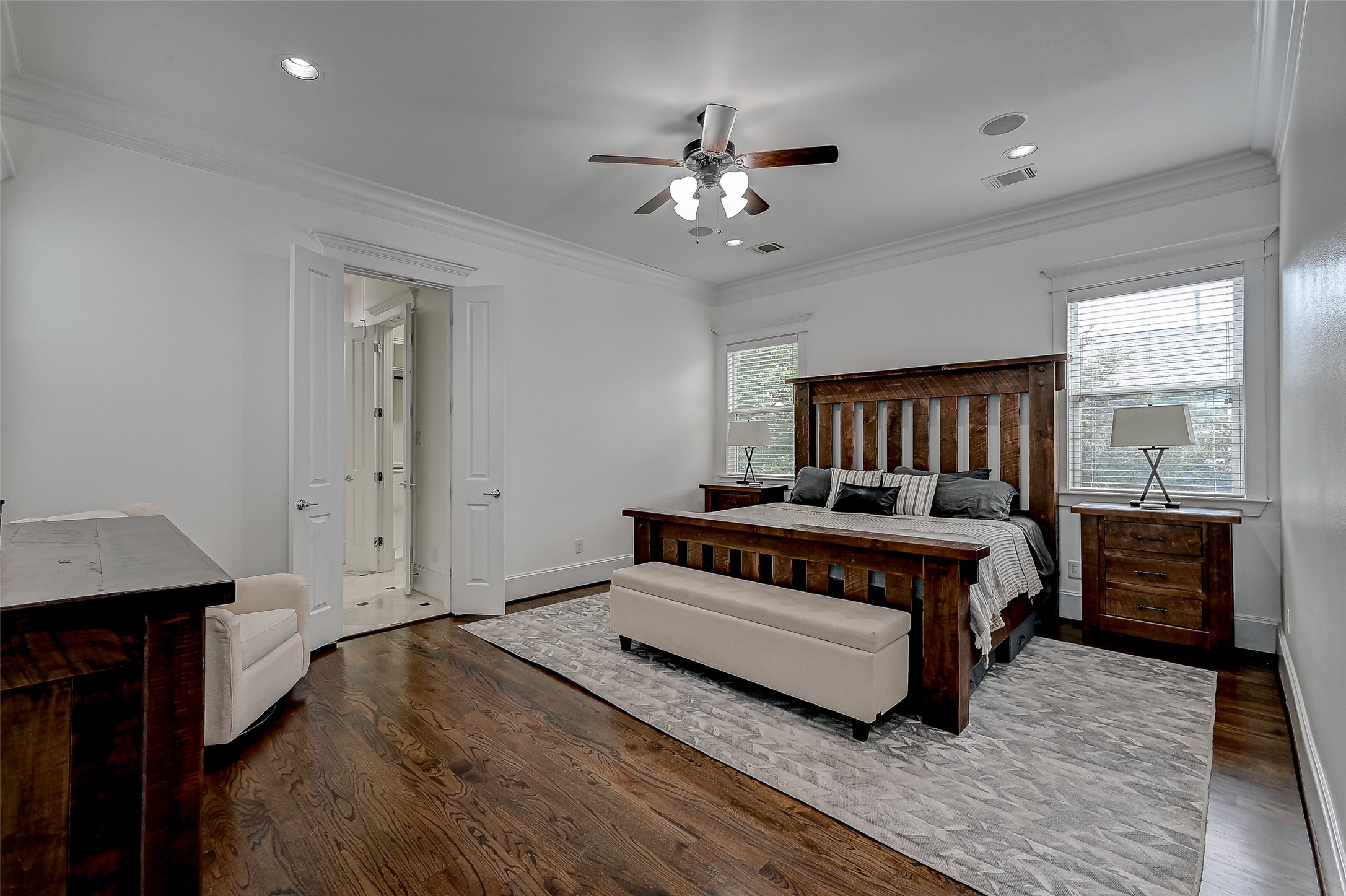 The primary bedroom is a sanctuary of luxury, featuring warm hardwood floors that offer a touch of comfort underfoot. High ceilings create an expansive atmosphere, while generous windows welcome abundant natural light.