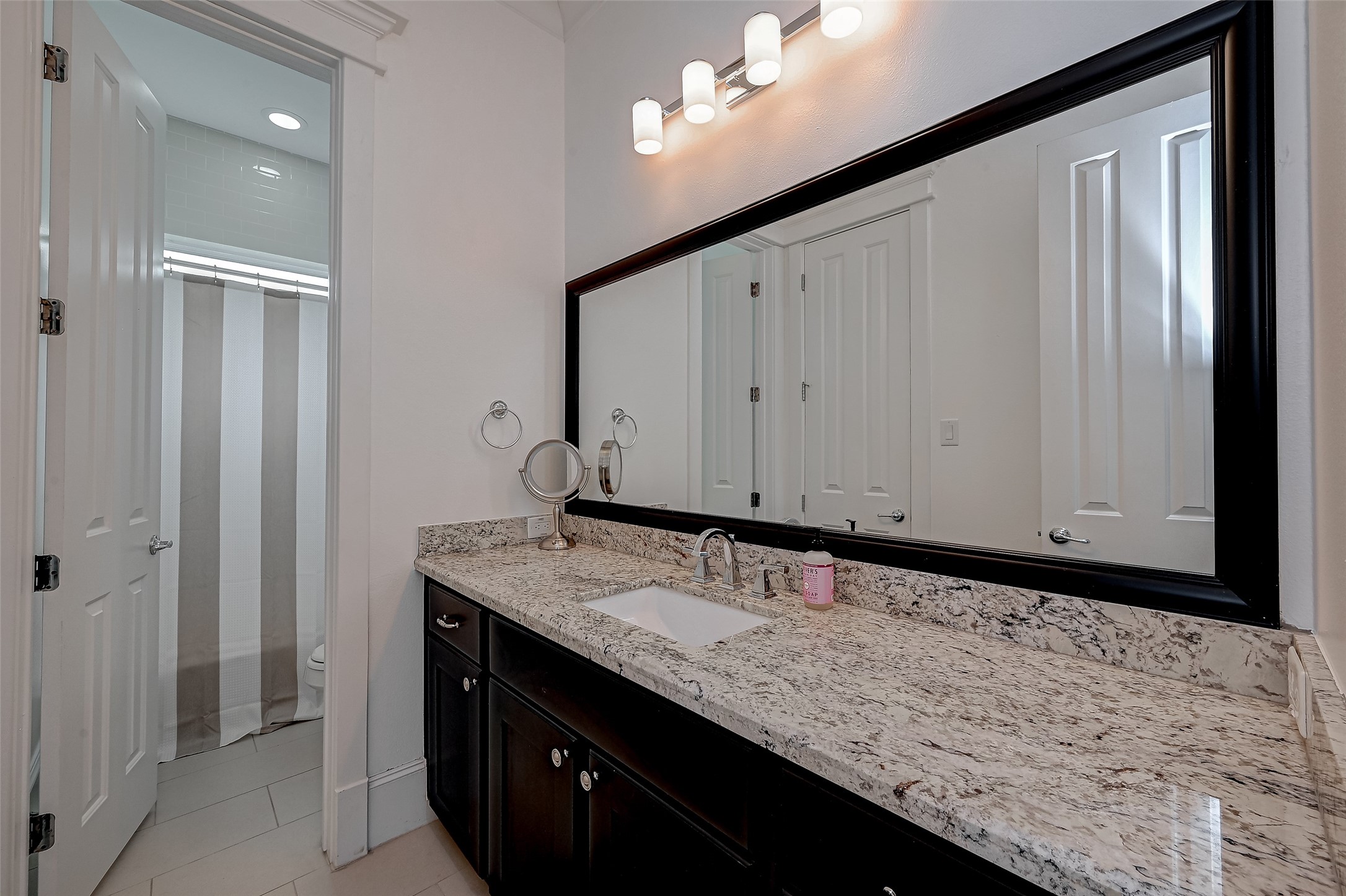 This thoughtfully designed bathroom creates an atmosphere of style and convenience, with a separate vanity area. This division allows for uninterrupted routines all within a single harmonious space.