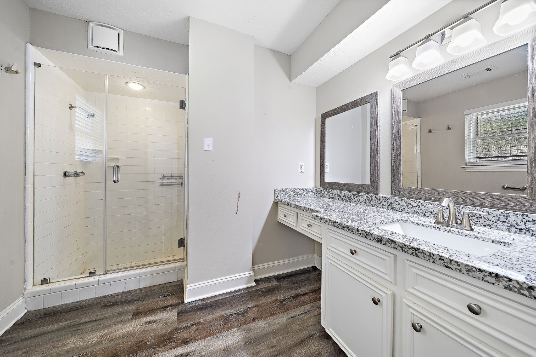 Updated primary bathroom with vanity area and beautiful granite countertops
