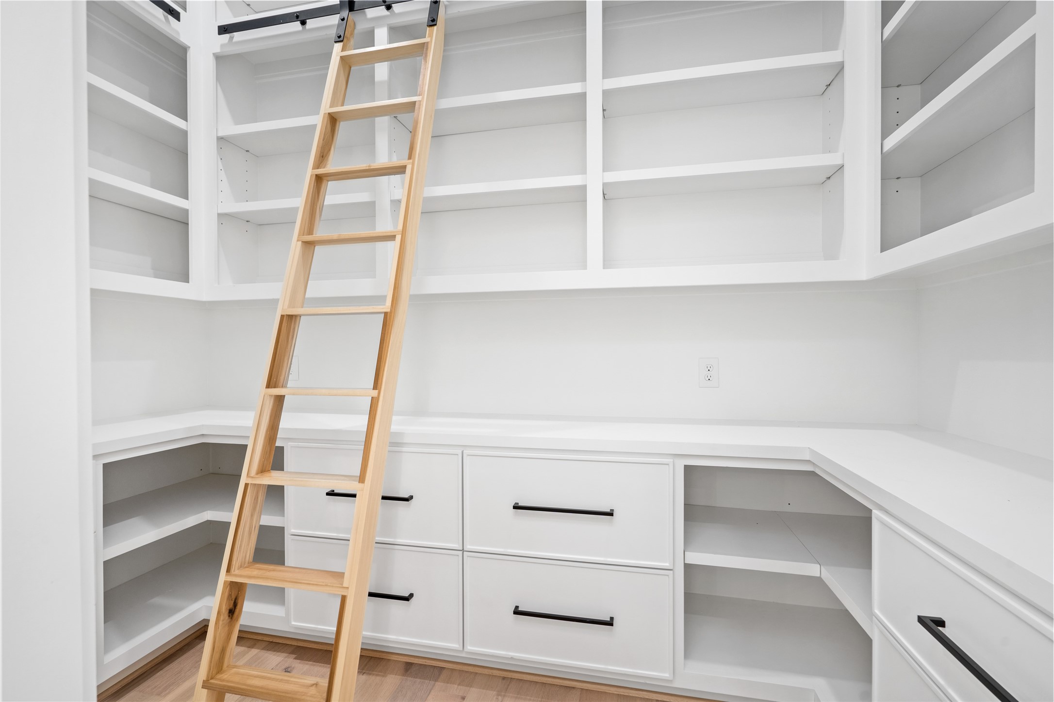 A favorite feature of mine is the huge walk-in pantry that includes counter space for kitchen appliances, outlets and a custom built ladder to provide access to storage out of reach. The slots on the right and left are perfect for lazy susans if you so choose!