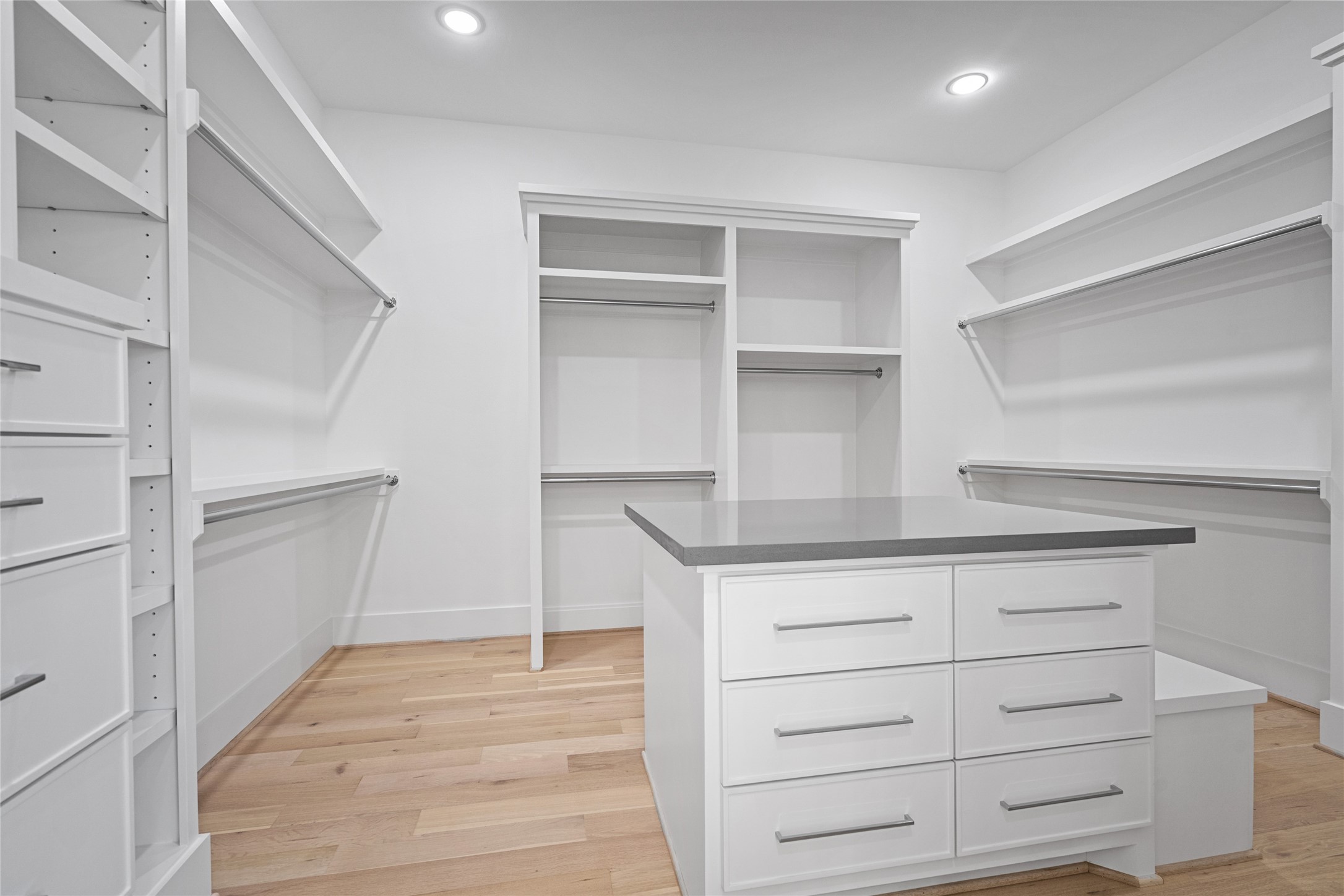 The primary closet includes tons of storage, creating space for longer garments, custom cabinetry and even a seat at the end of the island.