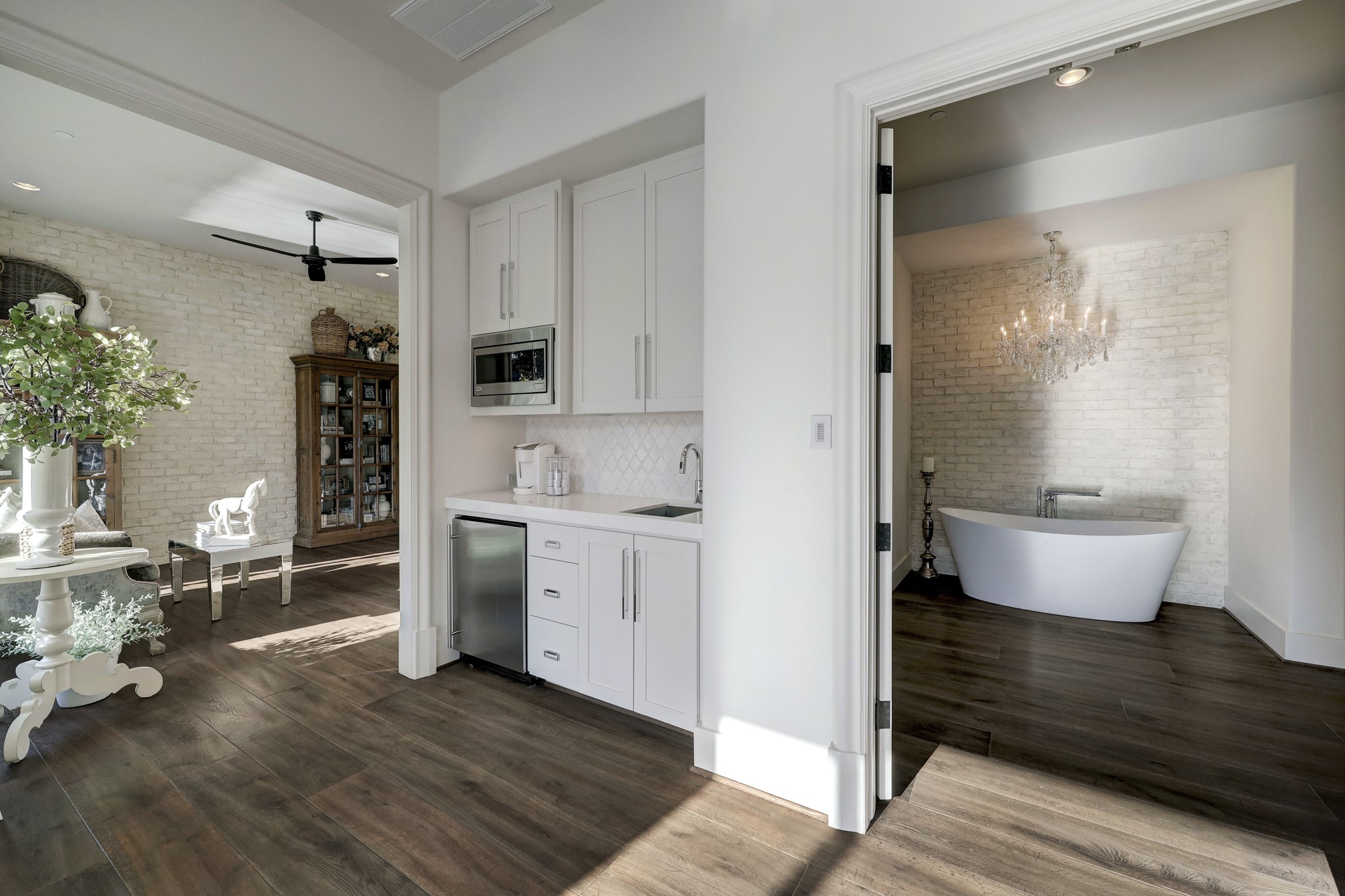 A vestibule to the primary bedroom features a convenient wet bar with a microwave, sink, ice maker, and quartz countertops, allowing for easy mornings.