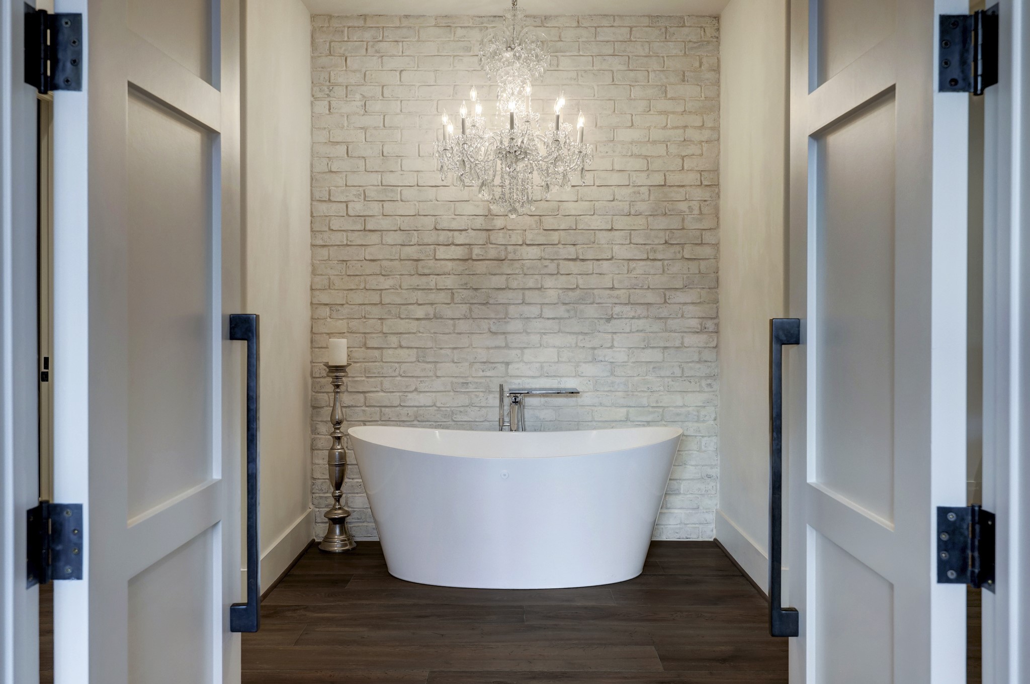 Upon entering the primary bathroom is a large soaking tub, with a dazzling glass chandelier above.