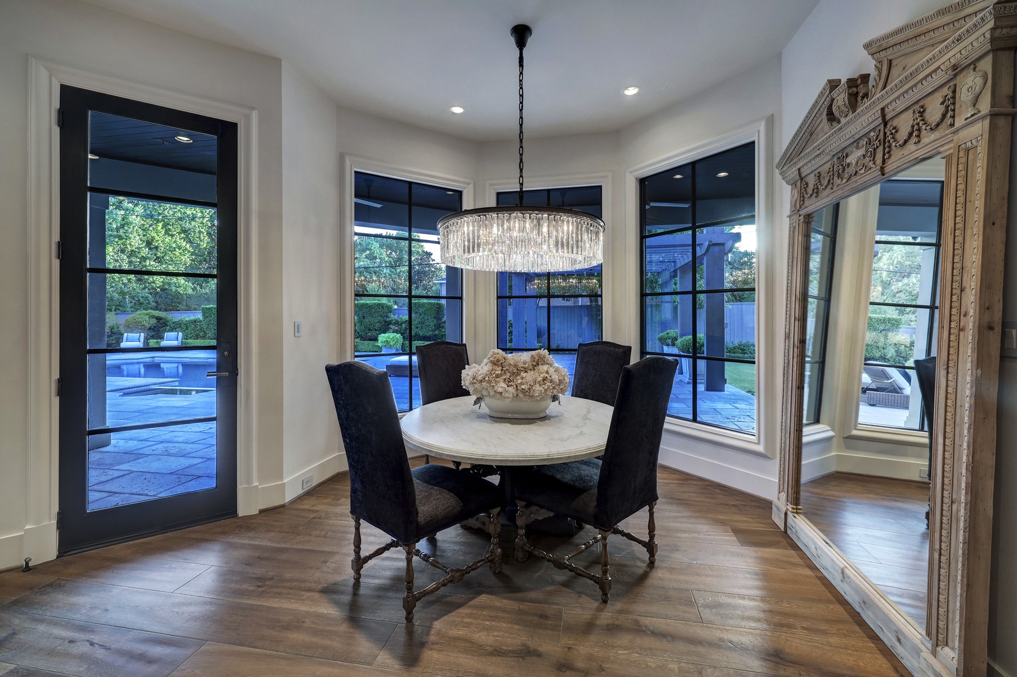 The sunny and bright breakfast room located off the kitchen features a striking glass chandelier, bay windows, and has a steel and glass door conveniently located to lead you outside.