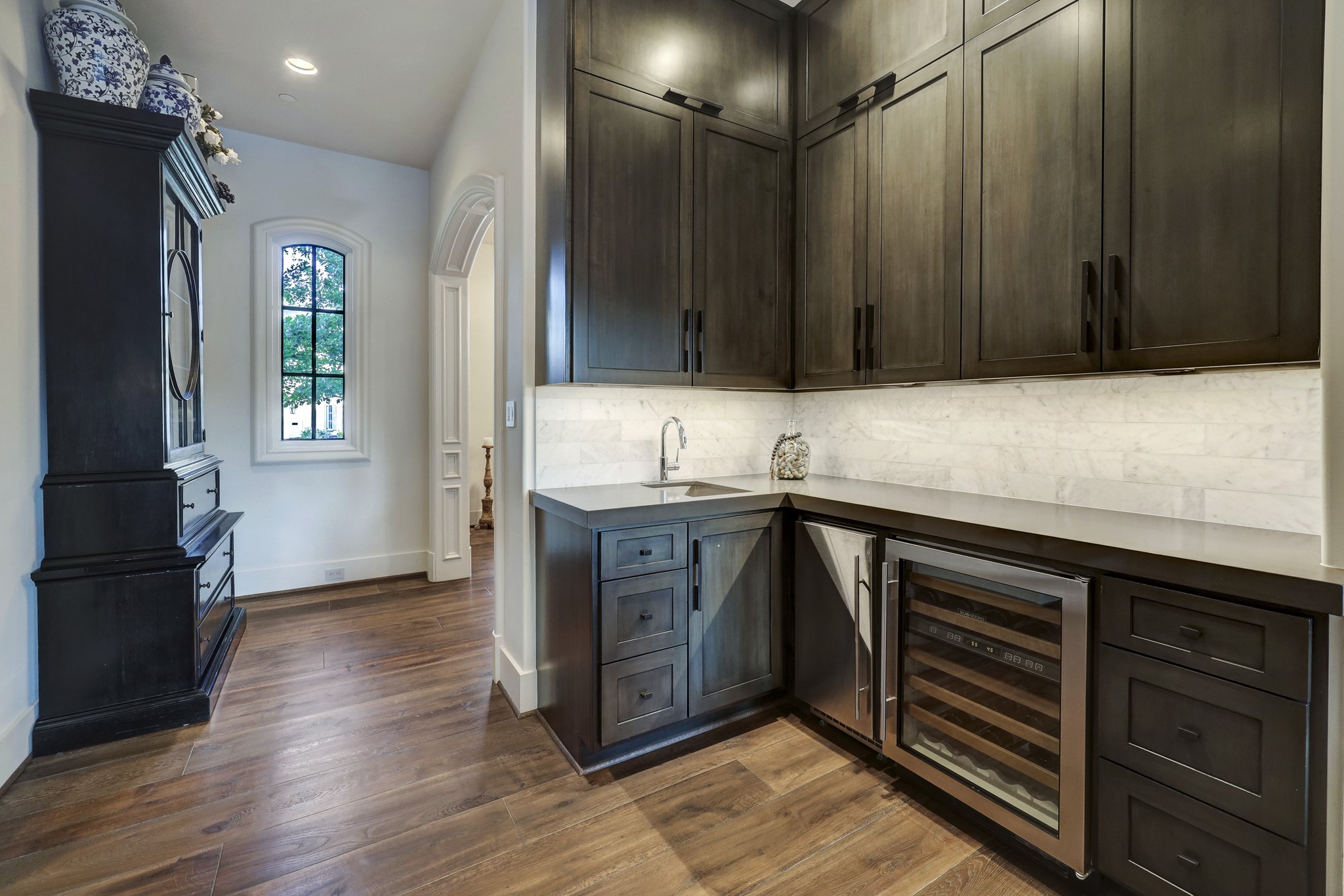 Located off the kitchen, the wet bar features a nugget ice maker, wine cooler, sink, and custom cabinetry with soft close cabinets and under cabinetry lighting.