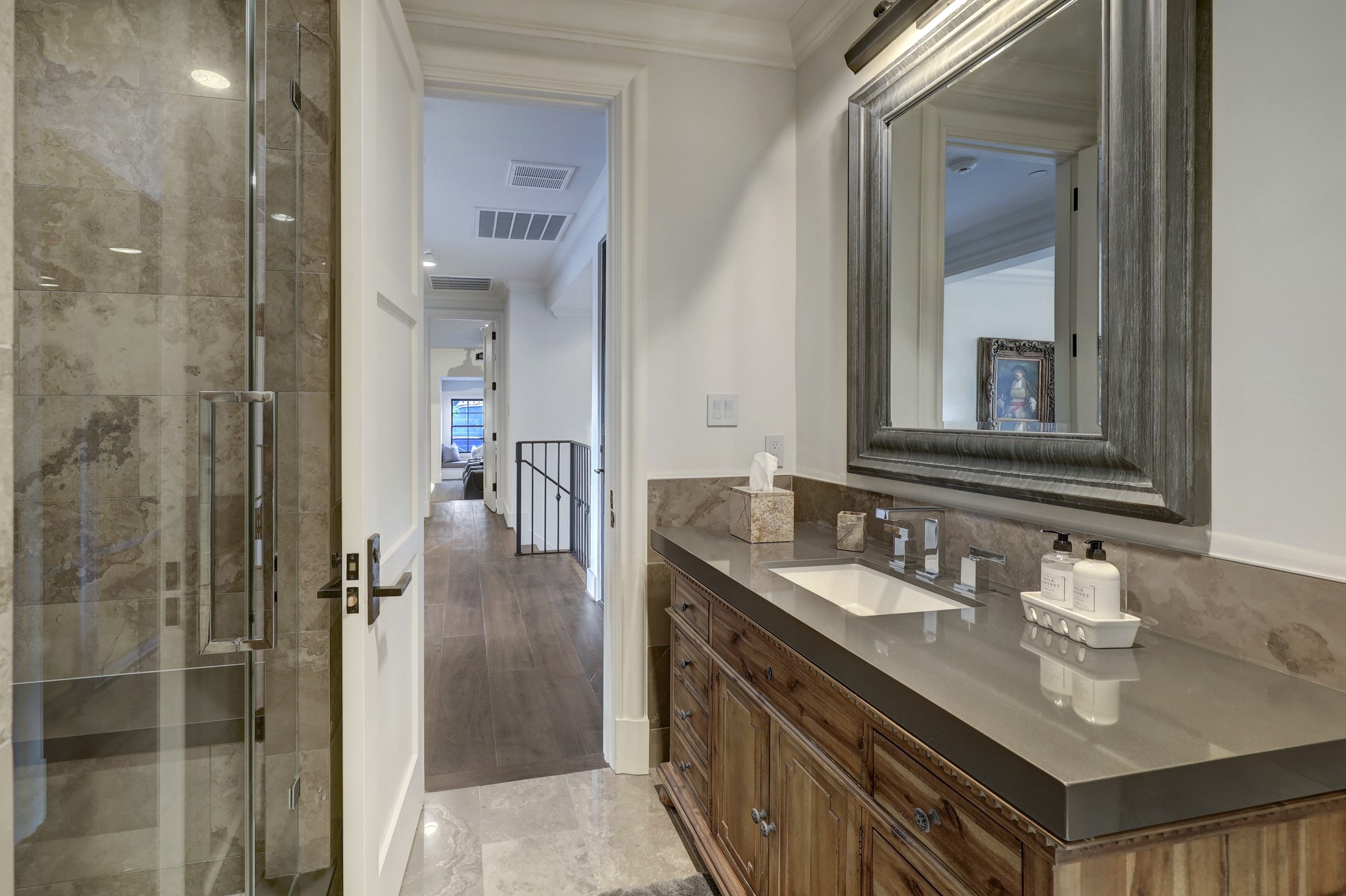 En-suite bathroom features dark grey quartz countertops and glass walk in shower.