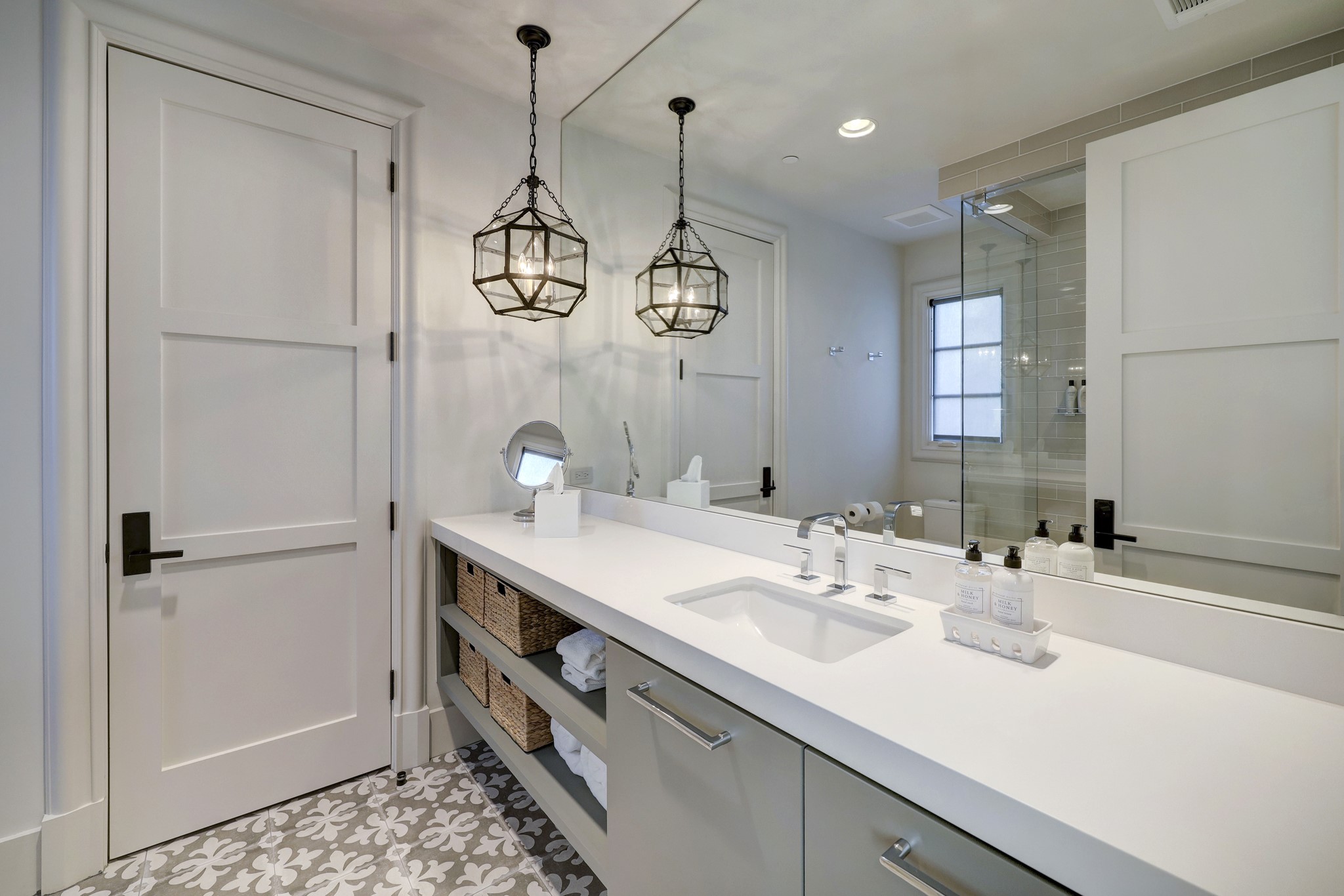 The en-suite bathroom has a floating vanity with quartz countertops, a walk-in shower with glass entry, and a steel and glass hanging pendant accent light.