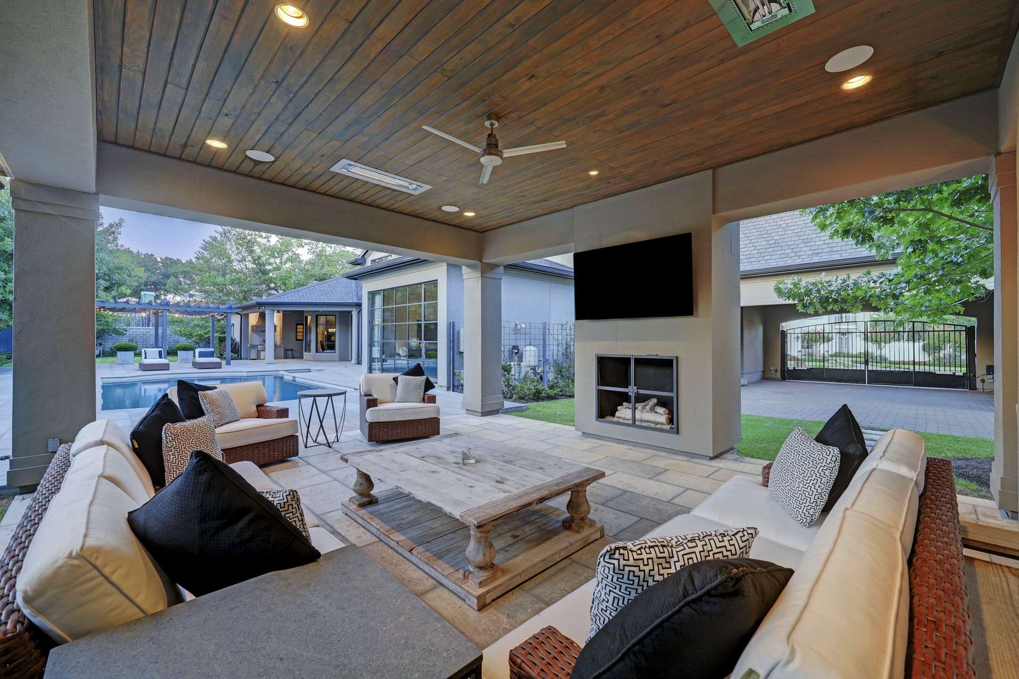 A stunning covered outdoor living area with a wood burning fireplace grants room to relax and entertain guests – the same reclaimed cherry wood floors from the guest quarters on the ceiling of this outdoor living space.