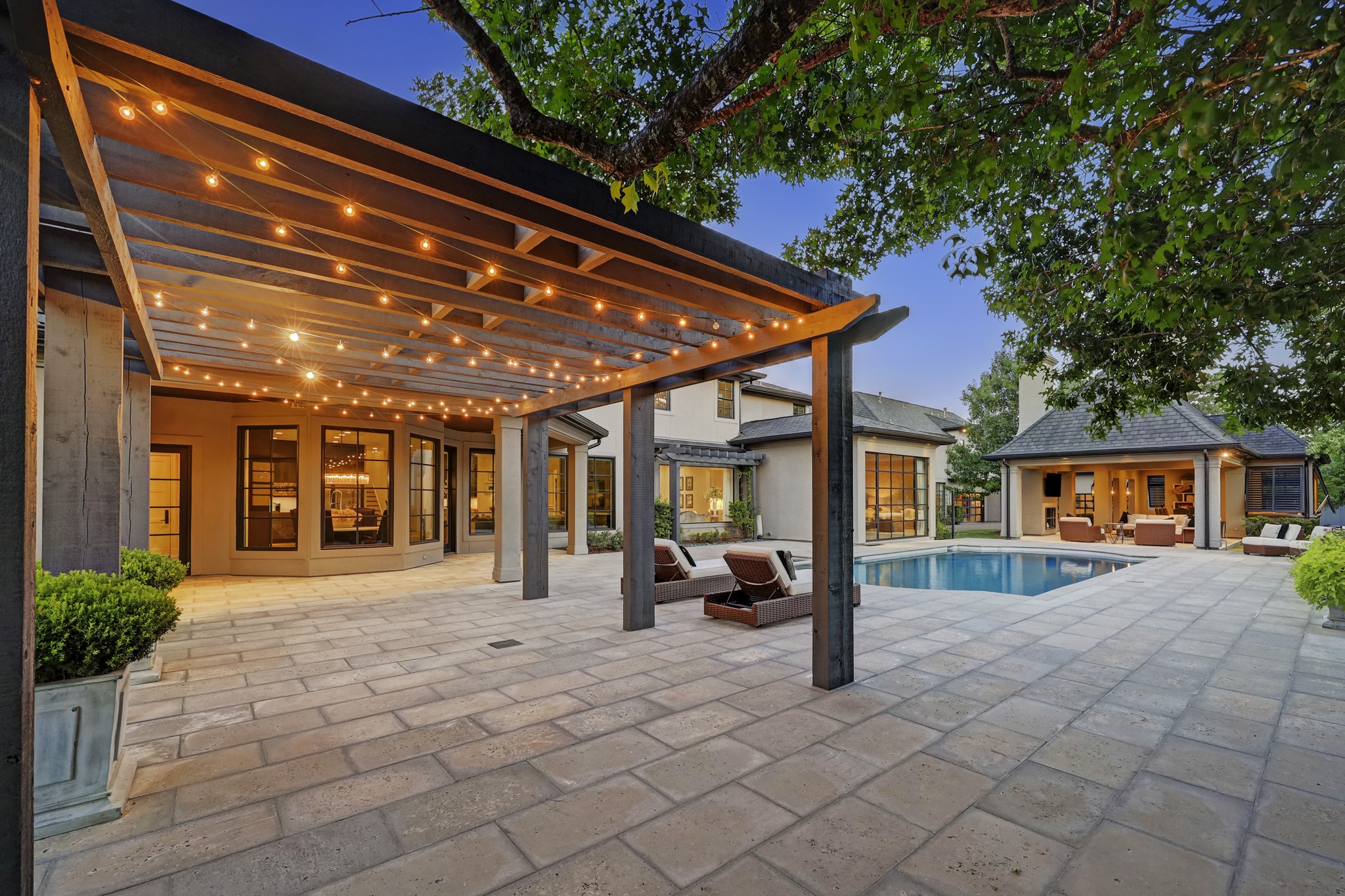 A wooden pergola covers a portion of the pavers, offering an opportunity to make this area whatever you desire – located conveniently next to the outdoor kitchen.