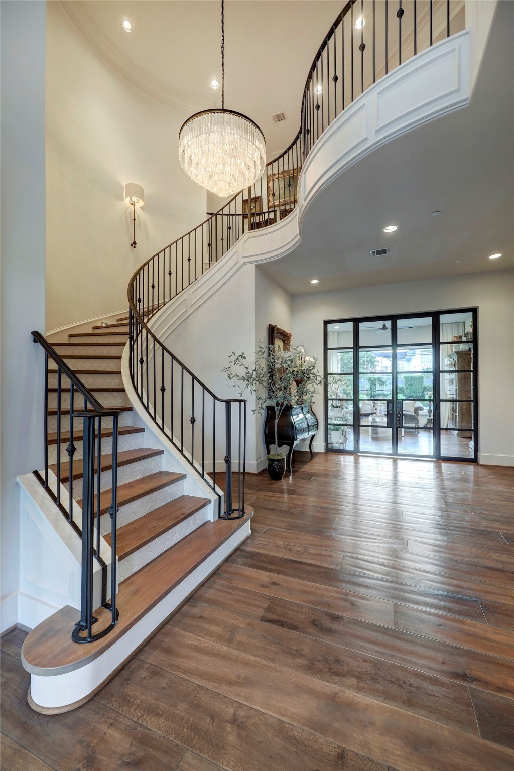 When you walk into the home, you are greeted with a large foyer with a wrought iron spiral staircase to lead you upstairs. Past the stairs leads you to the steel framed doors of your primary suite.