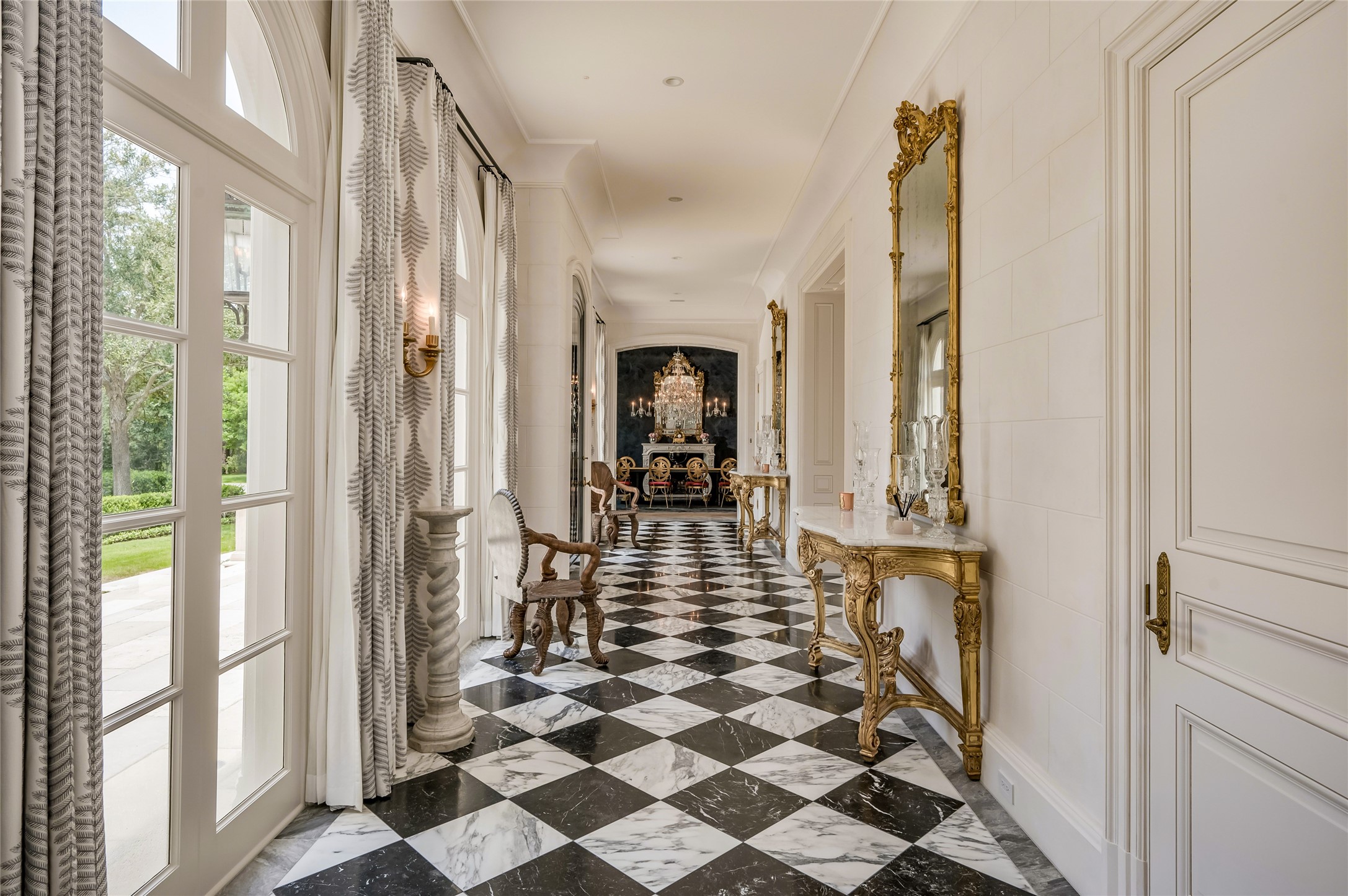 Black and white marble harlequin floors flow seamlessly through the grand foyer and formal living space.