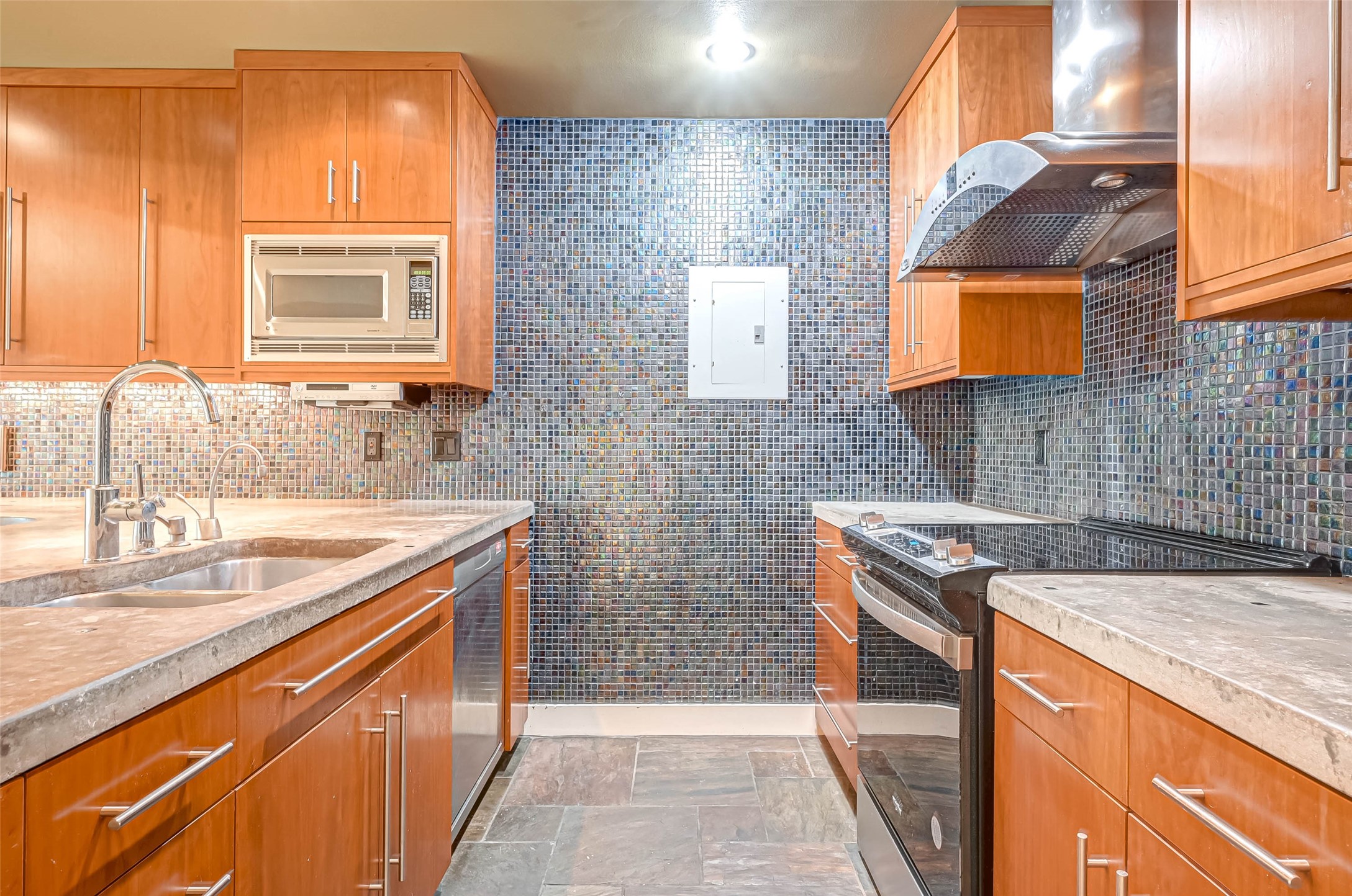 The kitchen features concrete counters, slate flooring, glass tile back splash and wall.  There is a great amount of cabinet storage, pot an pan drawers and wide drawers.