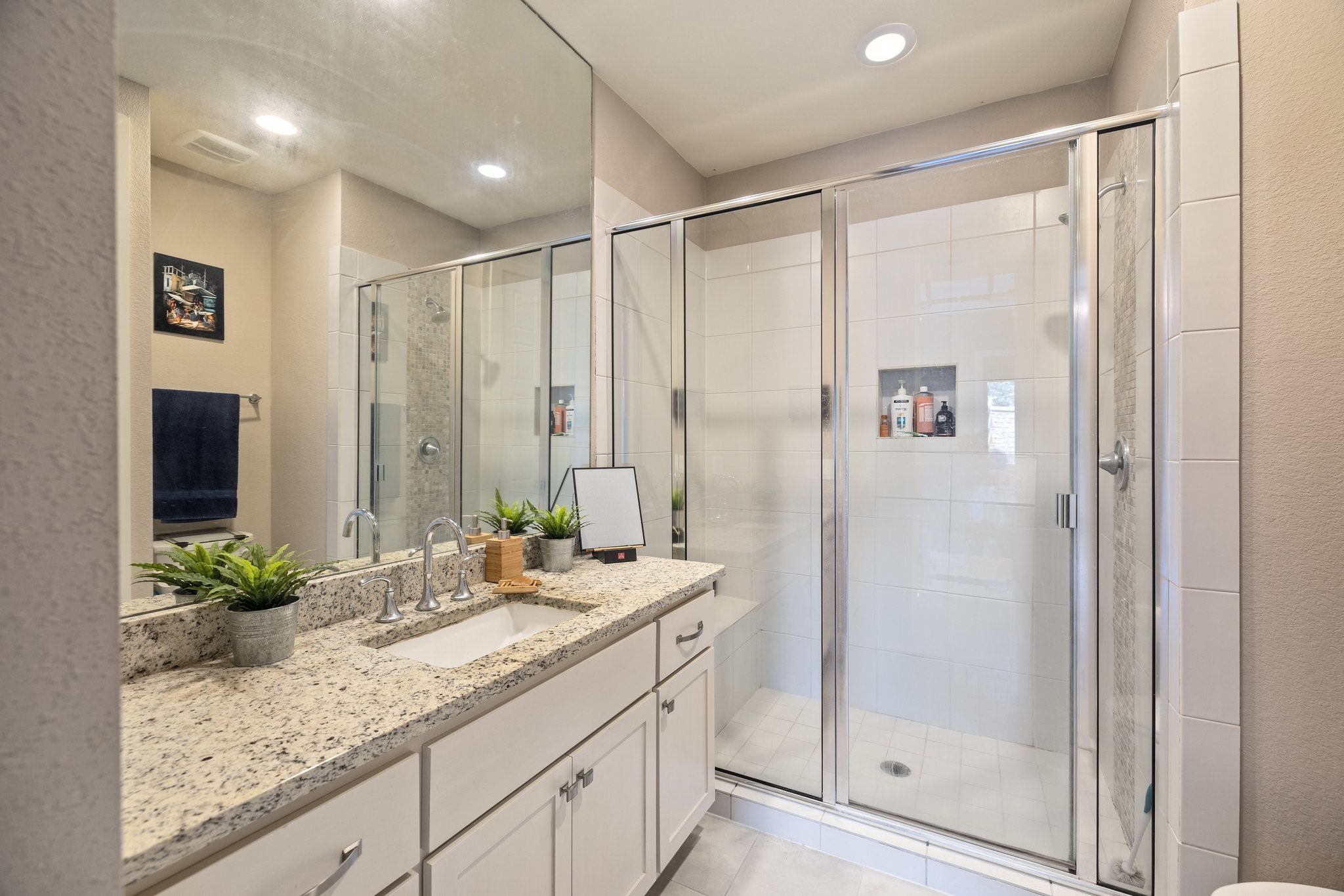 Secondary bathroom with tile accents/flooring, large mirrors and walk-in shower.