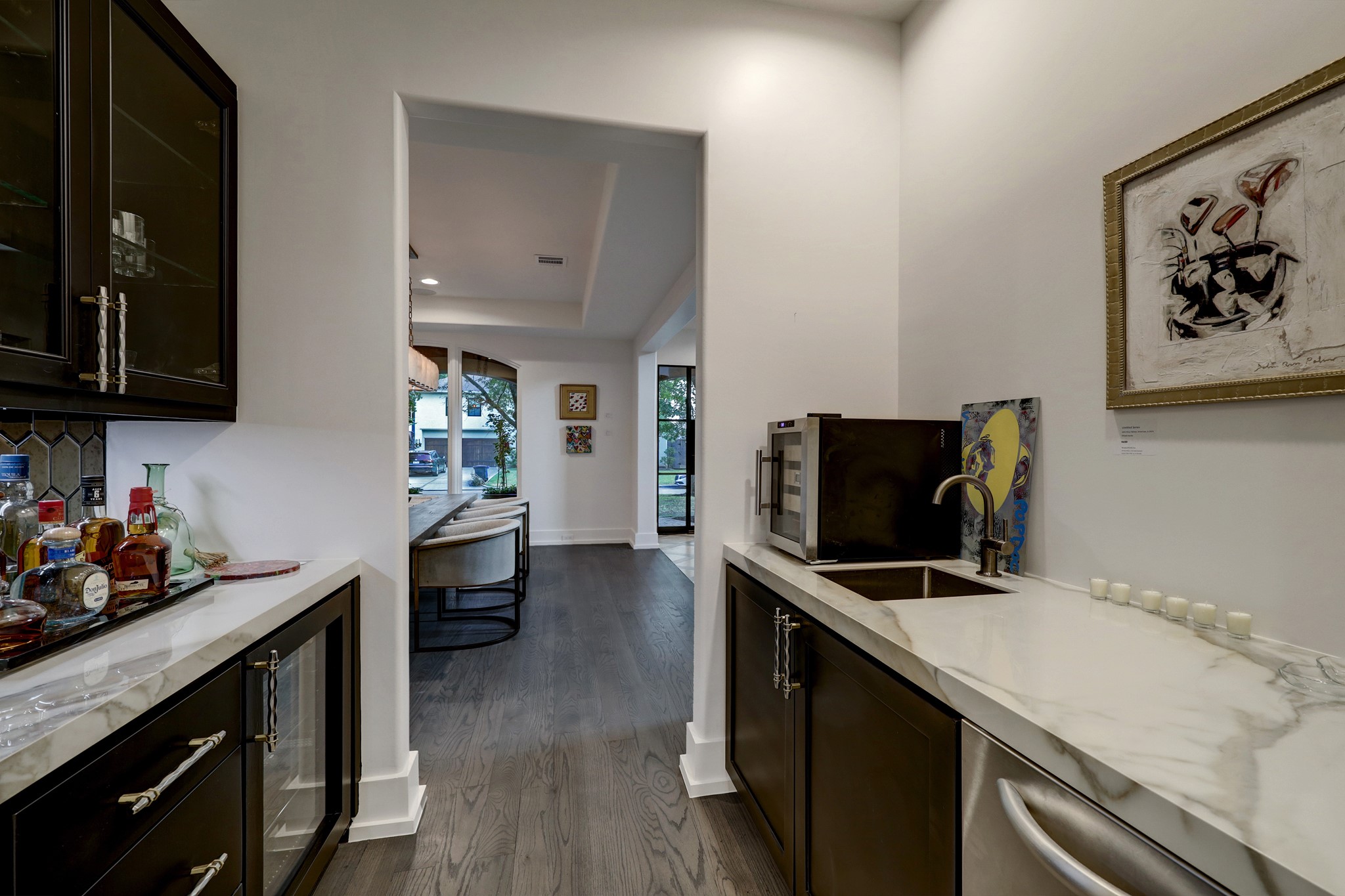 Between the dining room and the kitchen you'll find this amazing space for all your bar ware and storage. Featuring wet sink, wine fridge and glass front cabinets for storage. High quality hardware is throughout the home.