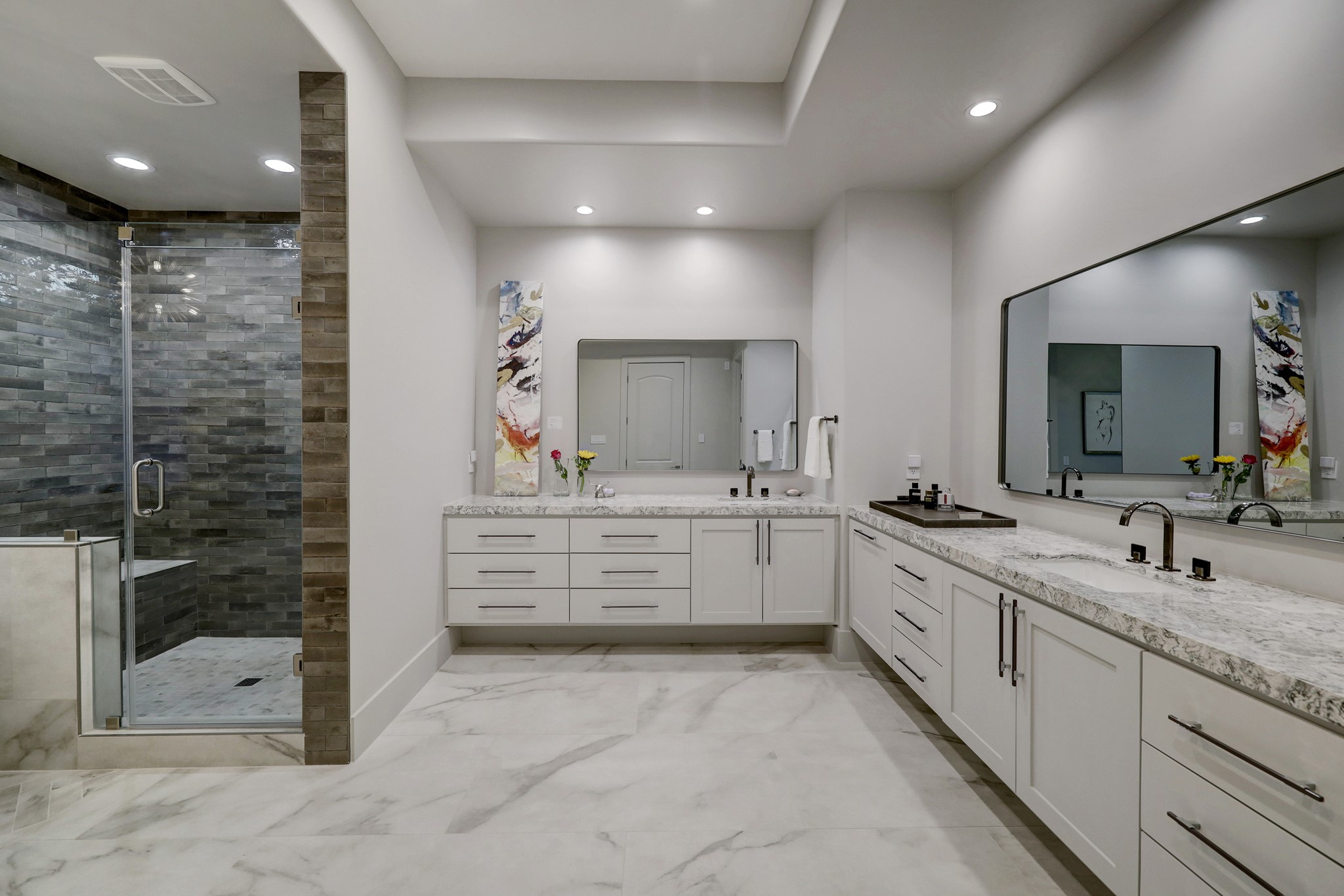 Opulent primary bath features dual vanities, custom fixtures, oversized, walk in shower and soaking tub.