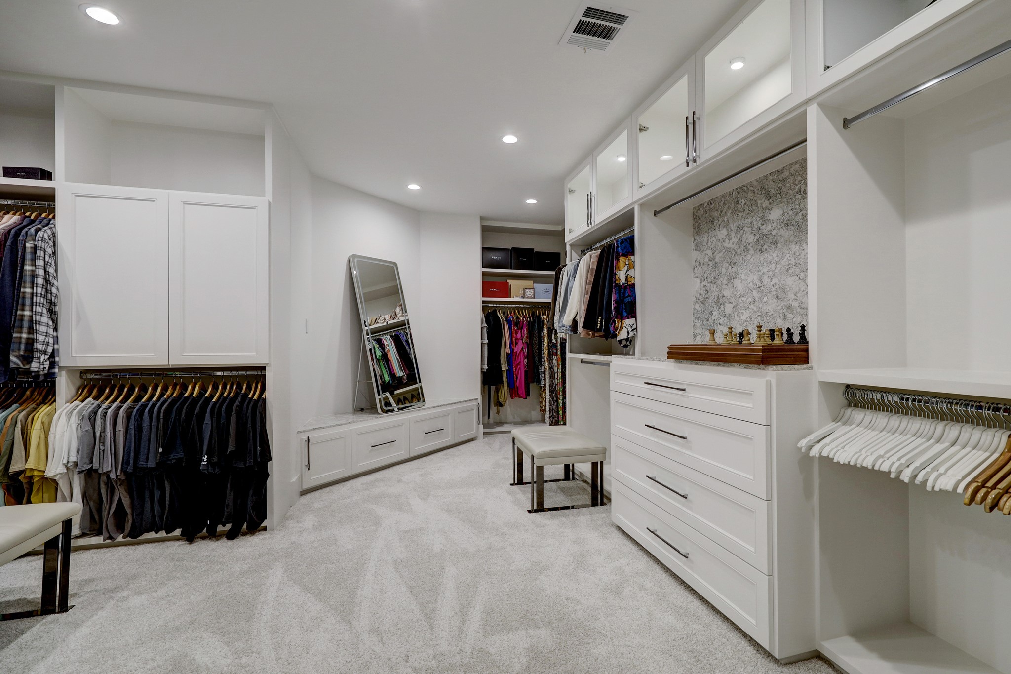 Well appointed closet with custom built ins, glass front cabinets and generous space for all your attire and more.