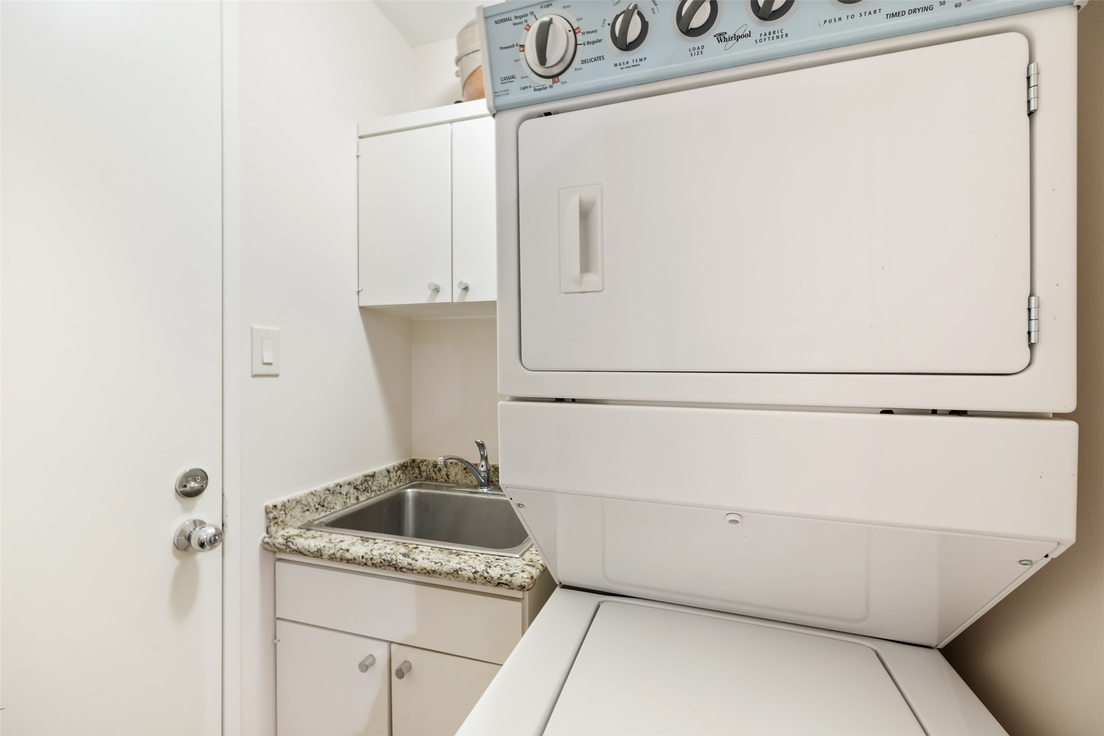 The utility room is designed for a stackable washer and dryer and is equipped with a sink and additional storage.