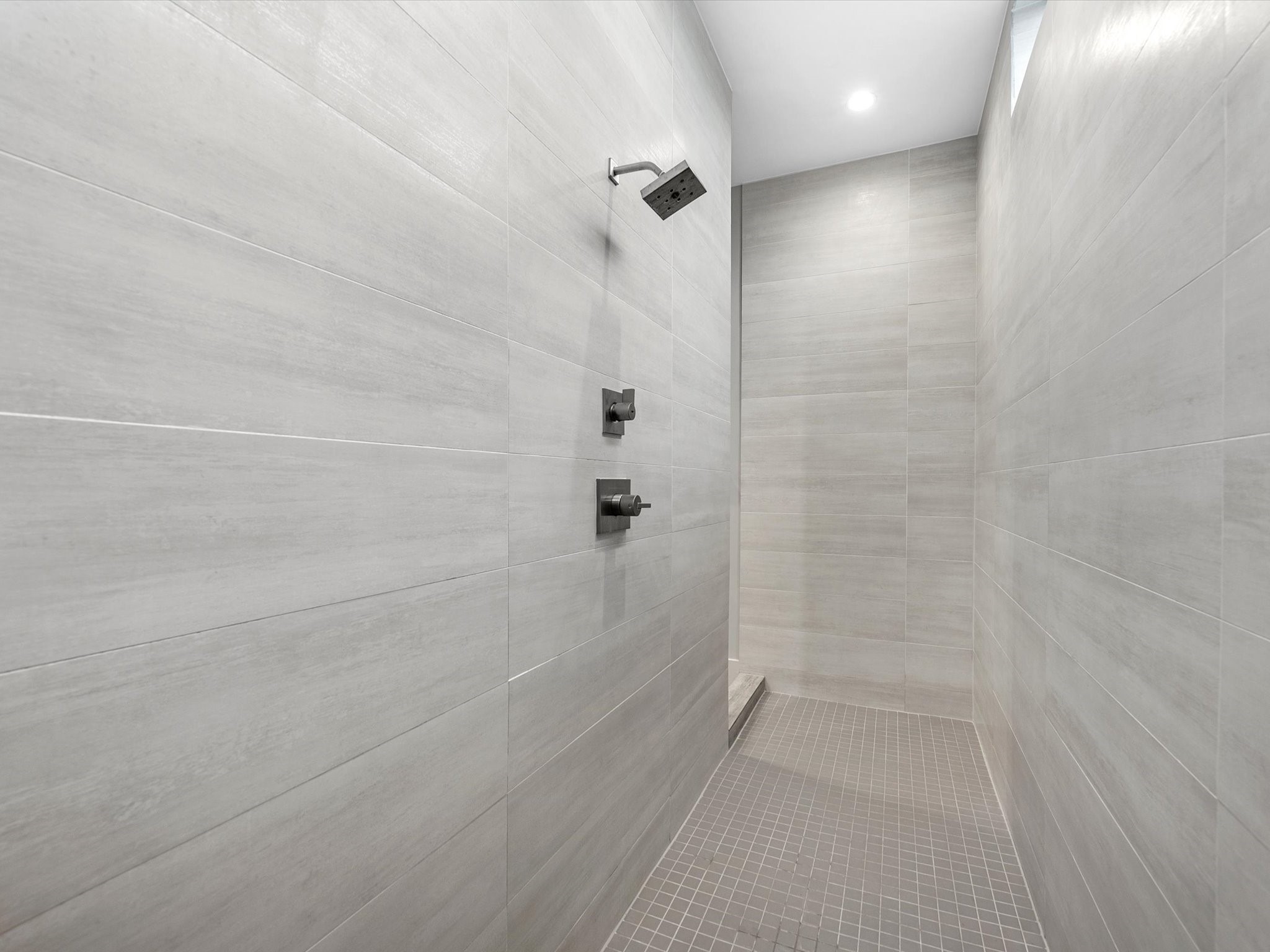 The walk-in shower features tile surround and recessed lighting!