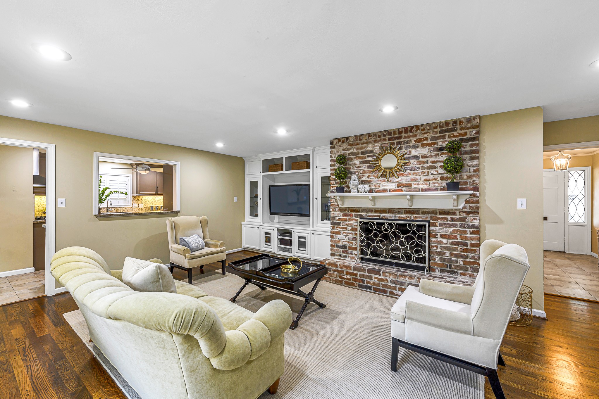 This space is adorned with a gas log brick fireplace, a warm and inviting paint palette, custom built-ins, and luxurious wood flooring, creating an ambiance that's perfect for relaxation and gatherings.