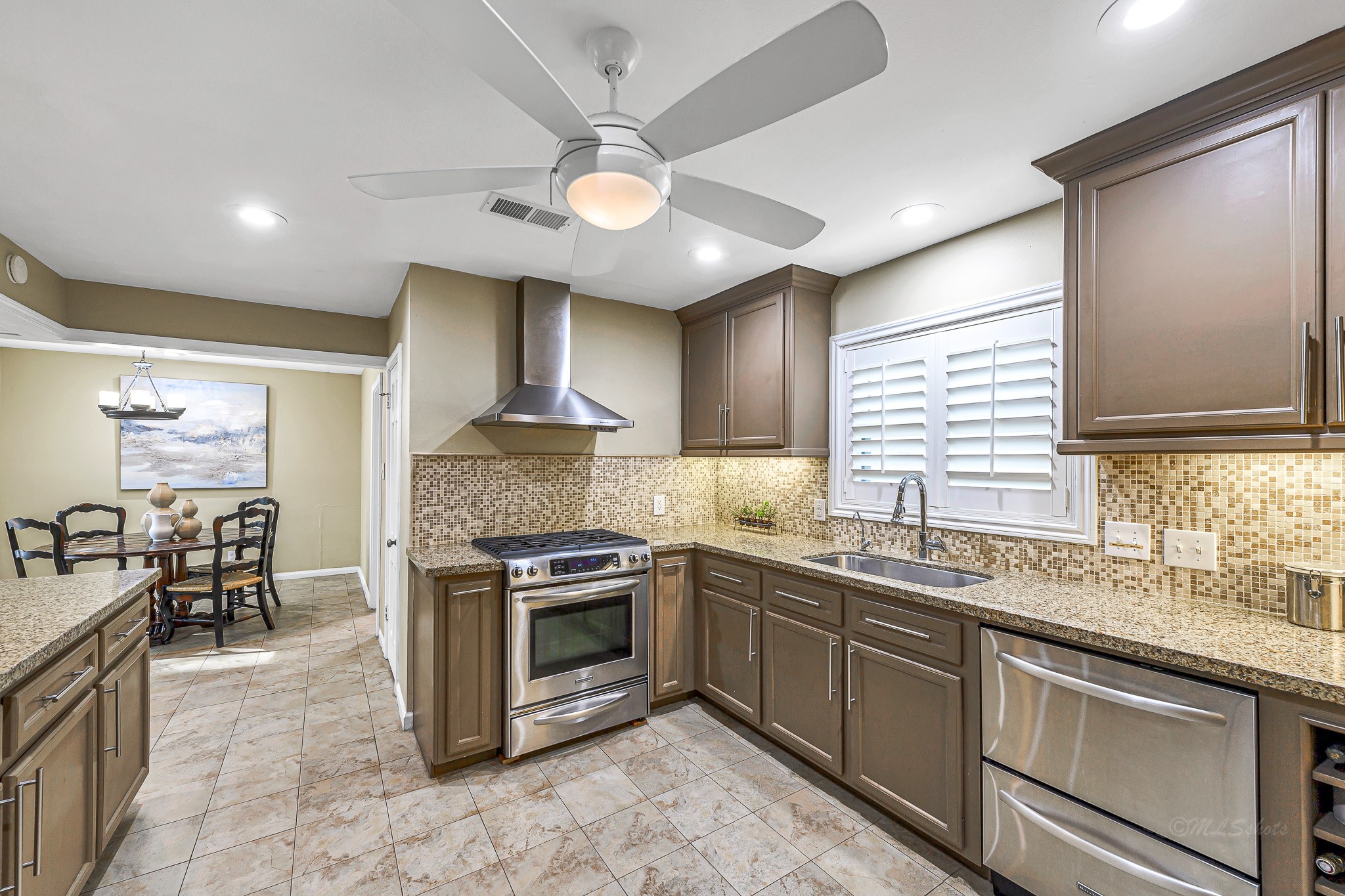 The stainless gas stove, double drawer dishwasher, granite countertops, neutral tones, and bright lighting come together to create a timeless and inviting culinary haven that's as functional as it is beautiful.