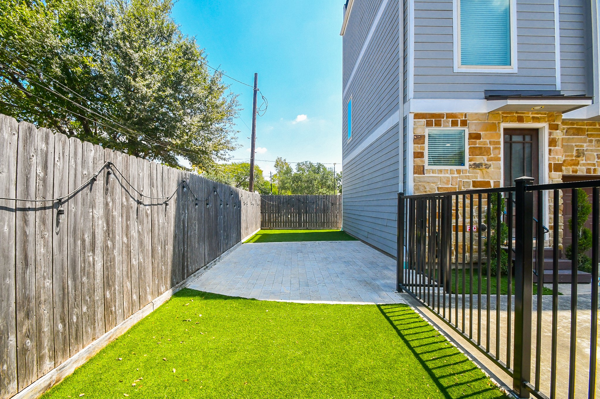 Fully Fenced private turfed side yard with stone-paved patio easily accessible from the front and back doors.