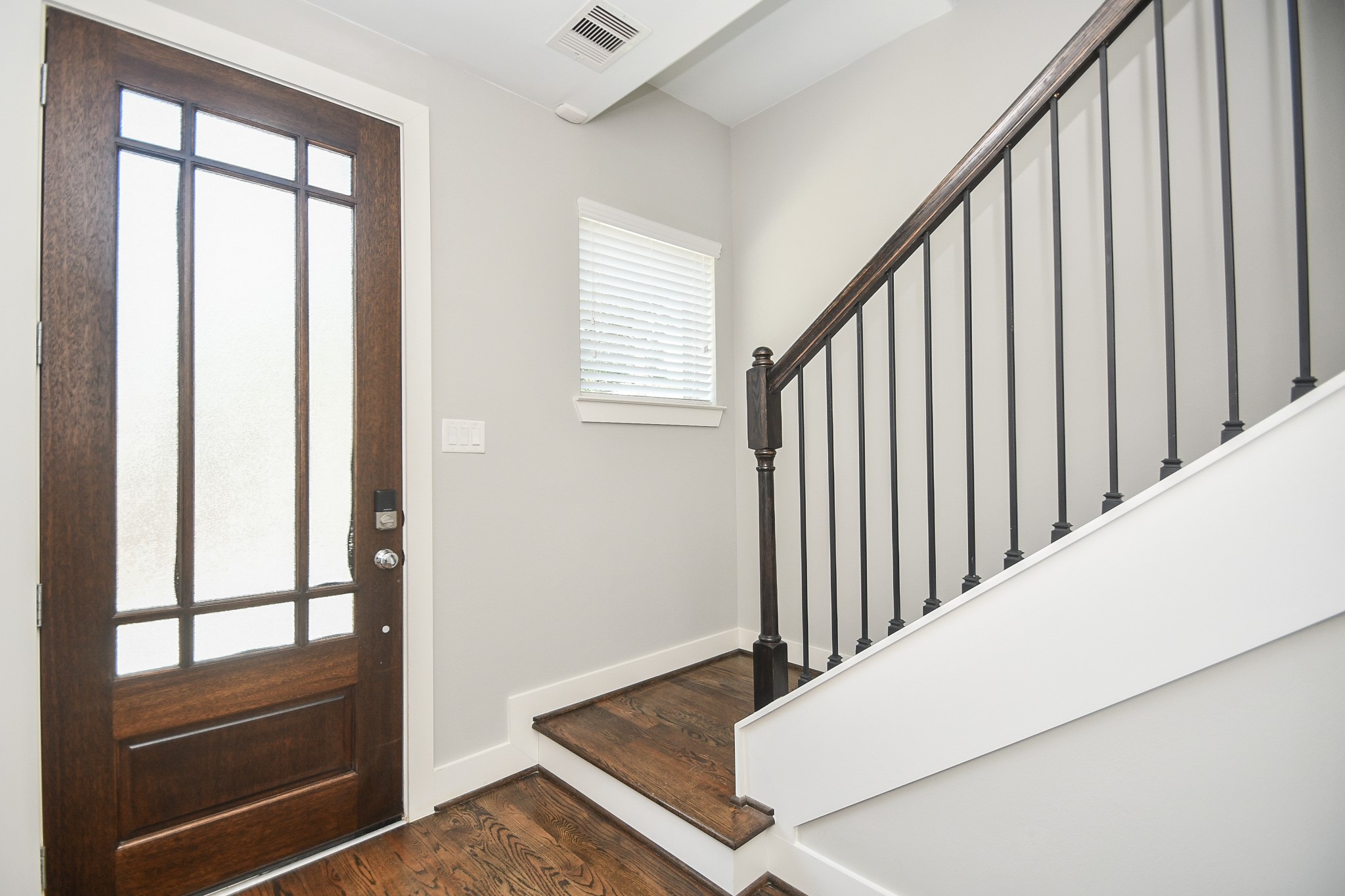 This is your neat, bright and welcoming front entry from the inside; with neutral walls and rich hardwood flooring guiding us to the stunning floors above.