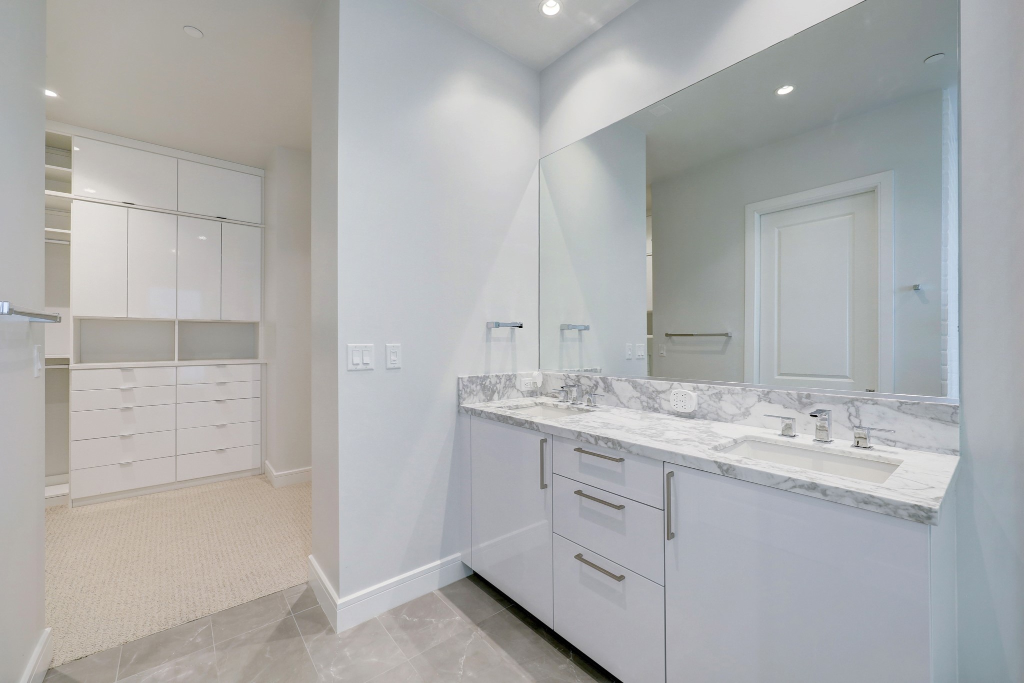 Primary Bathroom features tile floors, double vanity, large seamless glass shower and separate soaking tub. The bathroom leads to a walk-in closet with custom shelving