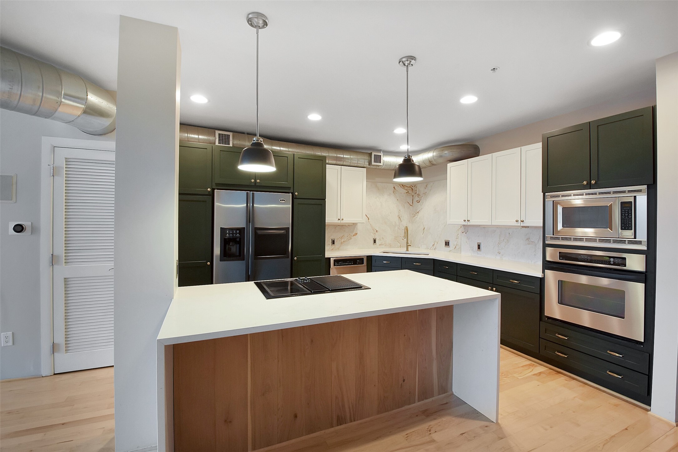 ADDITIONAL FEATURES INCLUDE STYLISH PENDANT AND RECESSED LIGHTING AND GLEAMING HARDWOOD FLOORING. THE ISLAND FEATURES ELECTRIC COOK TOP WITH GRIDDLE AND DOWN DRAFT VENTILATION. BONUS THE REFRIGERATOR STAYS!