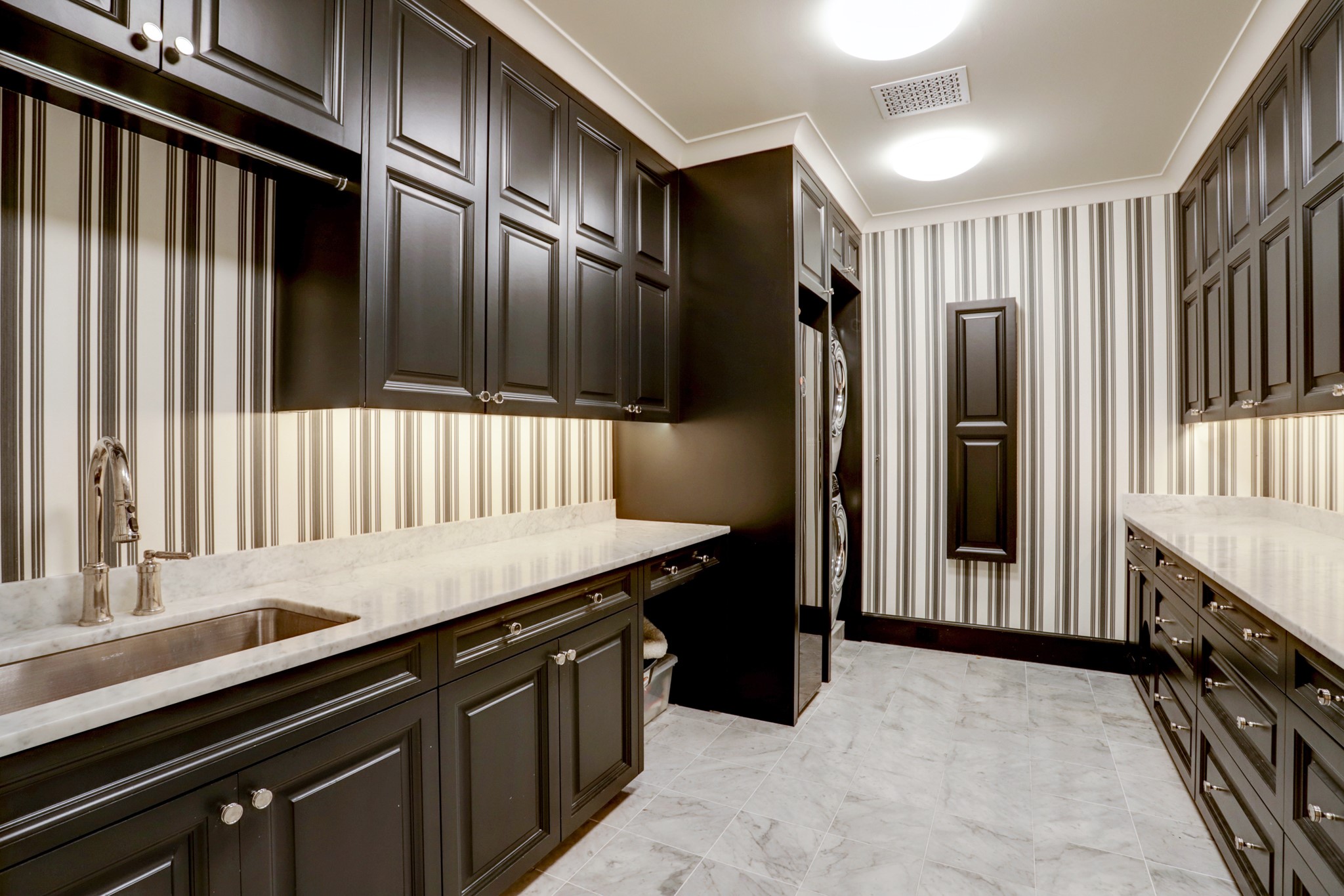 Utility Room: LG clothing steamer appliance. Carrara marble countertop & flooring. Built-ins with soft close cabinets & drawers with under cabinet lighting. Sink with nickel hardware and silver nickel hardware. Stackable washer & dryer. Refrigerator. Built-in fold out ironing board.
