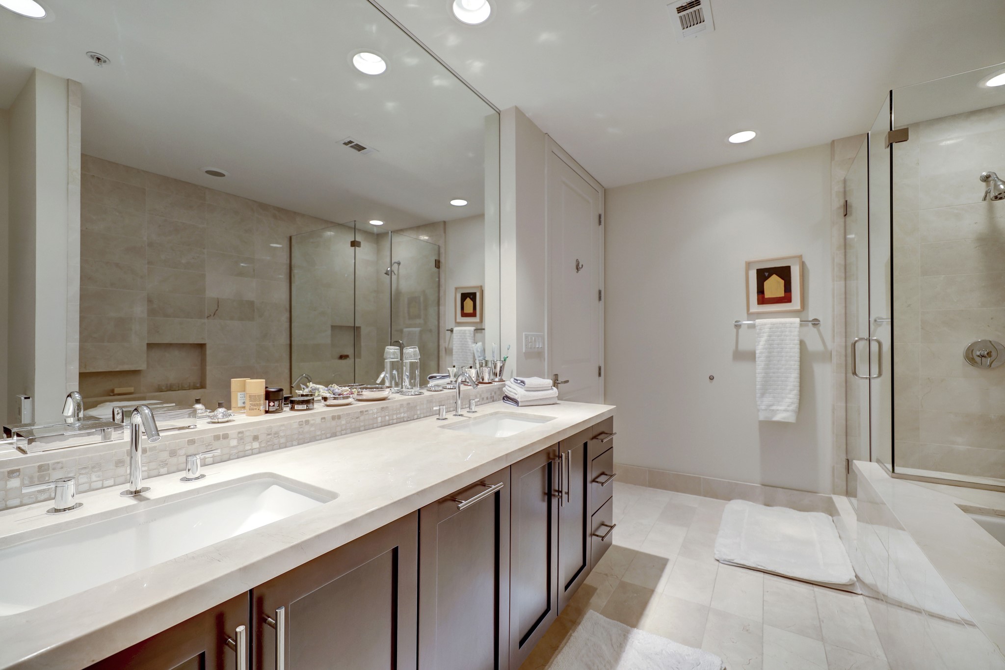 The Primary bath has double sinks, marble counters, wood cabinetry jetted tub and separate glass-wall shower.