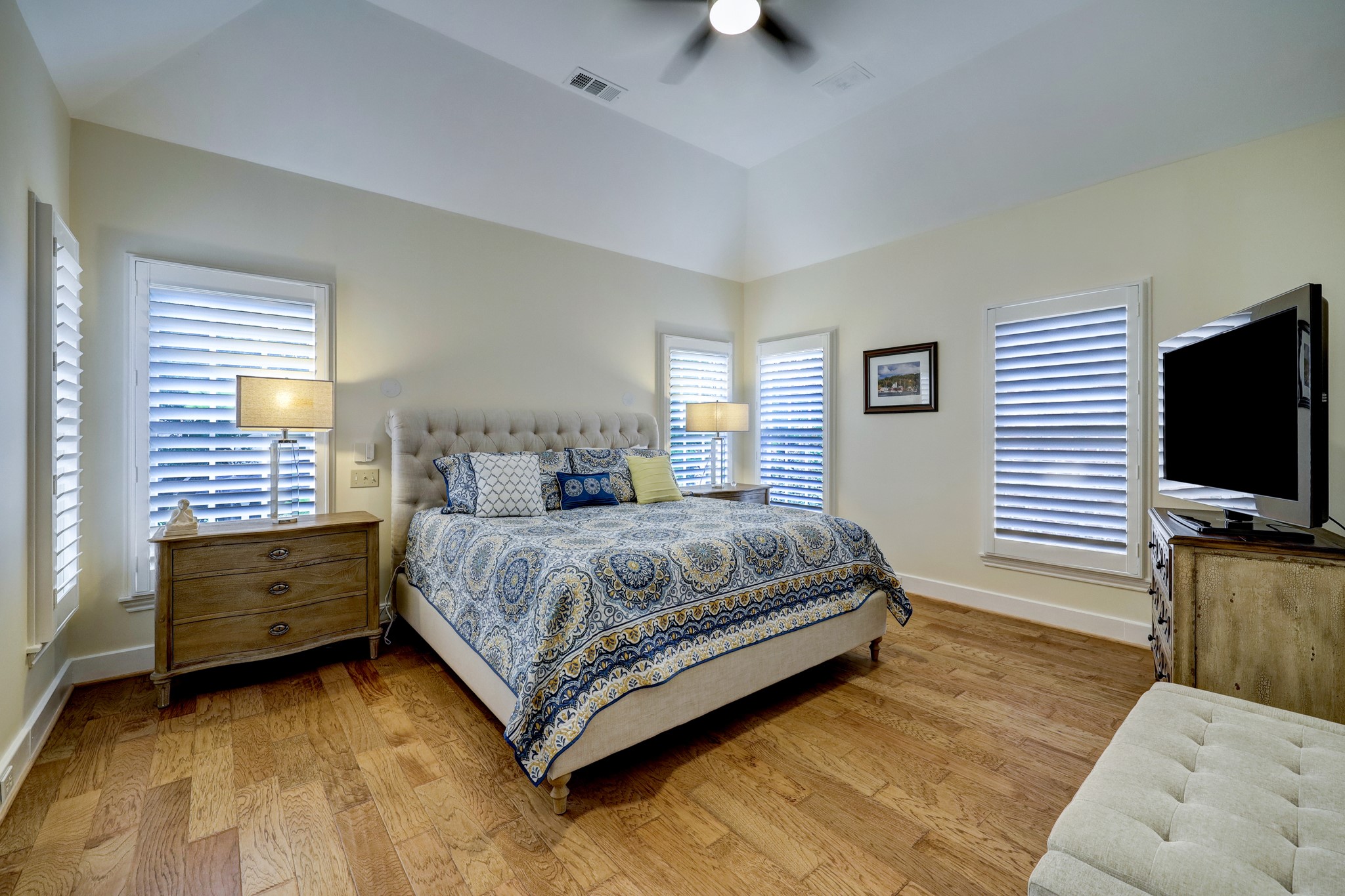 The primary bedroom with hardwood floors and tons of ambient light. Custom shutters.