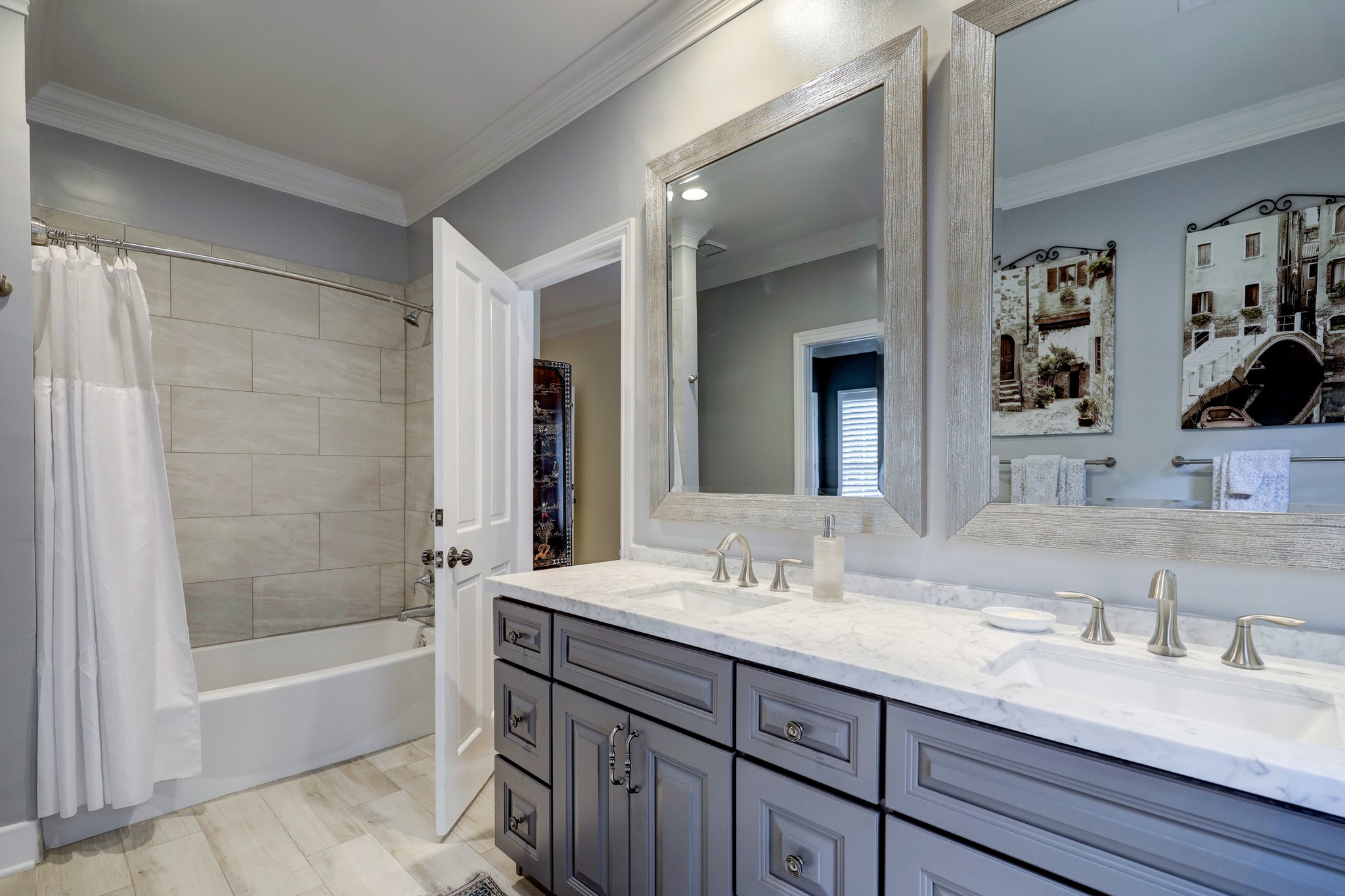 Completely remodeled, the secondary bath now features dual sinks, designer mirrors, on-trend tile and neutral colors.