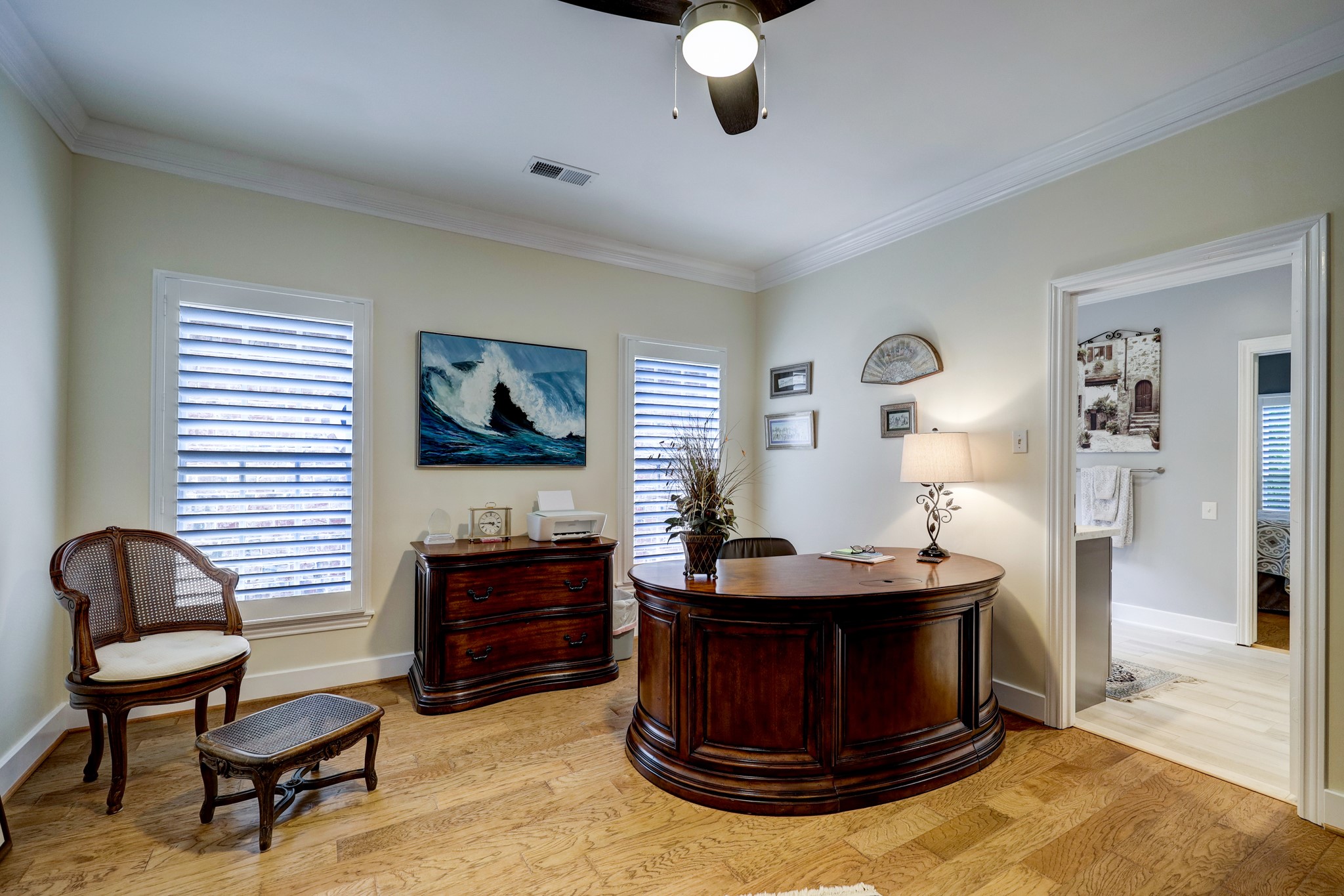 Currently being used as a home office, this secondary bedroom also features hardwood floors, ceiling fan and custom shutters.