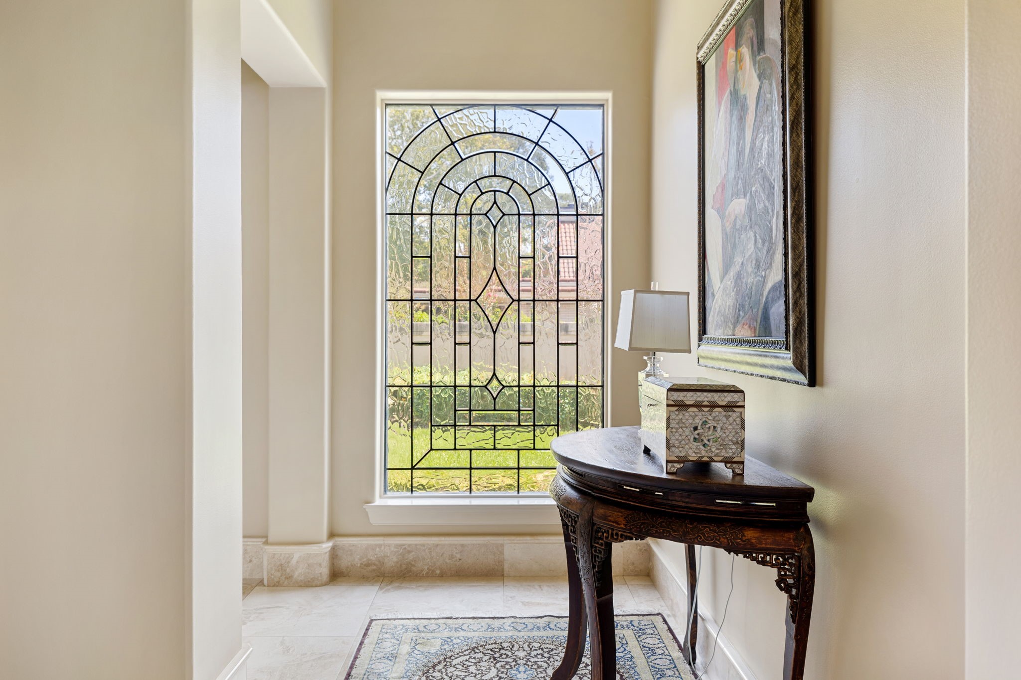 On the final axis of the Grand Foyer is a artful, private hallway that welcomes you to the secluded Master Suite. A gorgeous custom leaded glass window adds prisms of clear light to the space.
