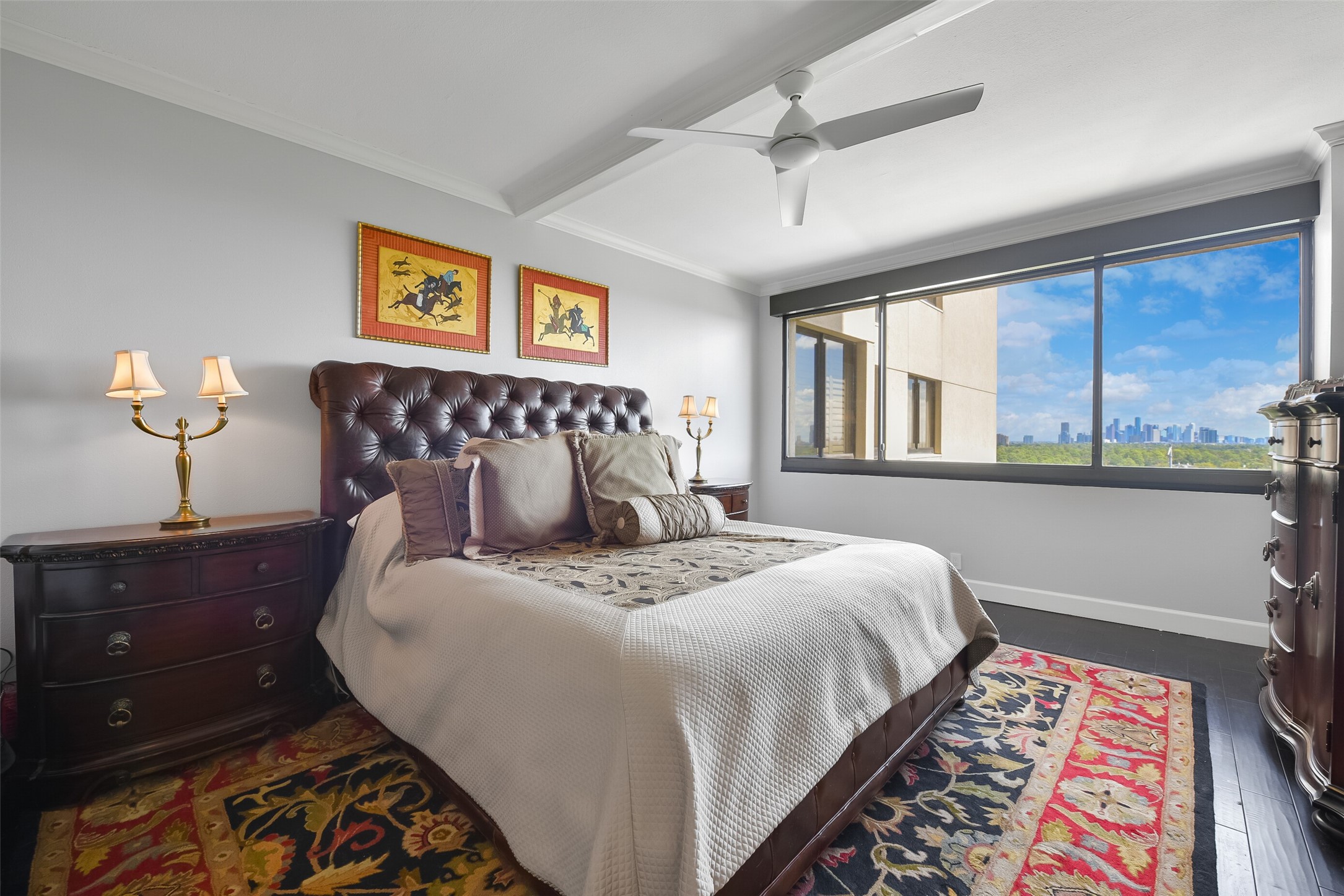 Retreat to the primary bedroom, featuring a large picture window framing stunning sunrise views of downtown and Memorial Park.