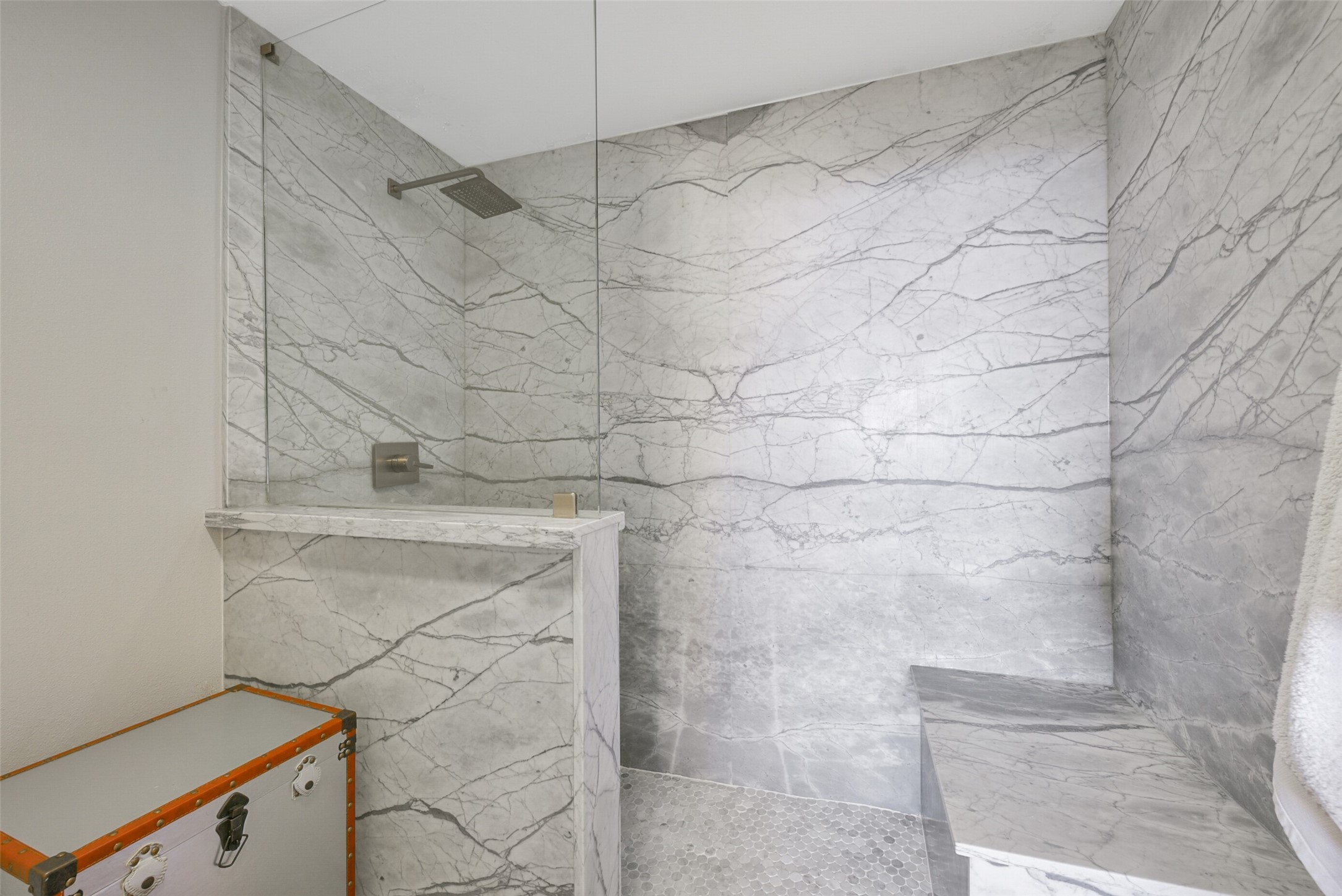 The primary bath also features an oversized marble shower with bench seat, frameless glass and rain shower head.