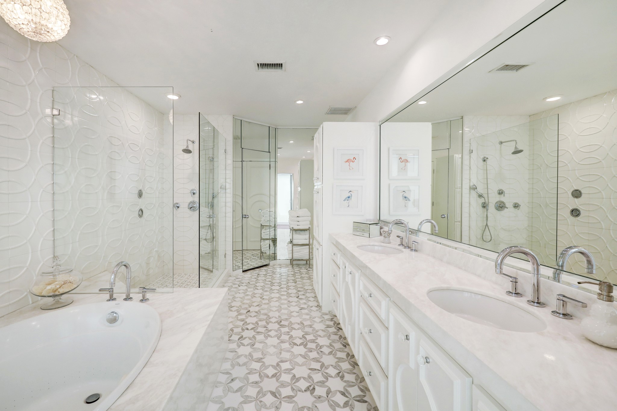 Serene primary bath with walk-in shower, intricate tile accents, tub and double sinks.
