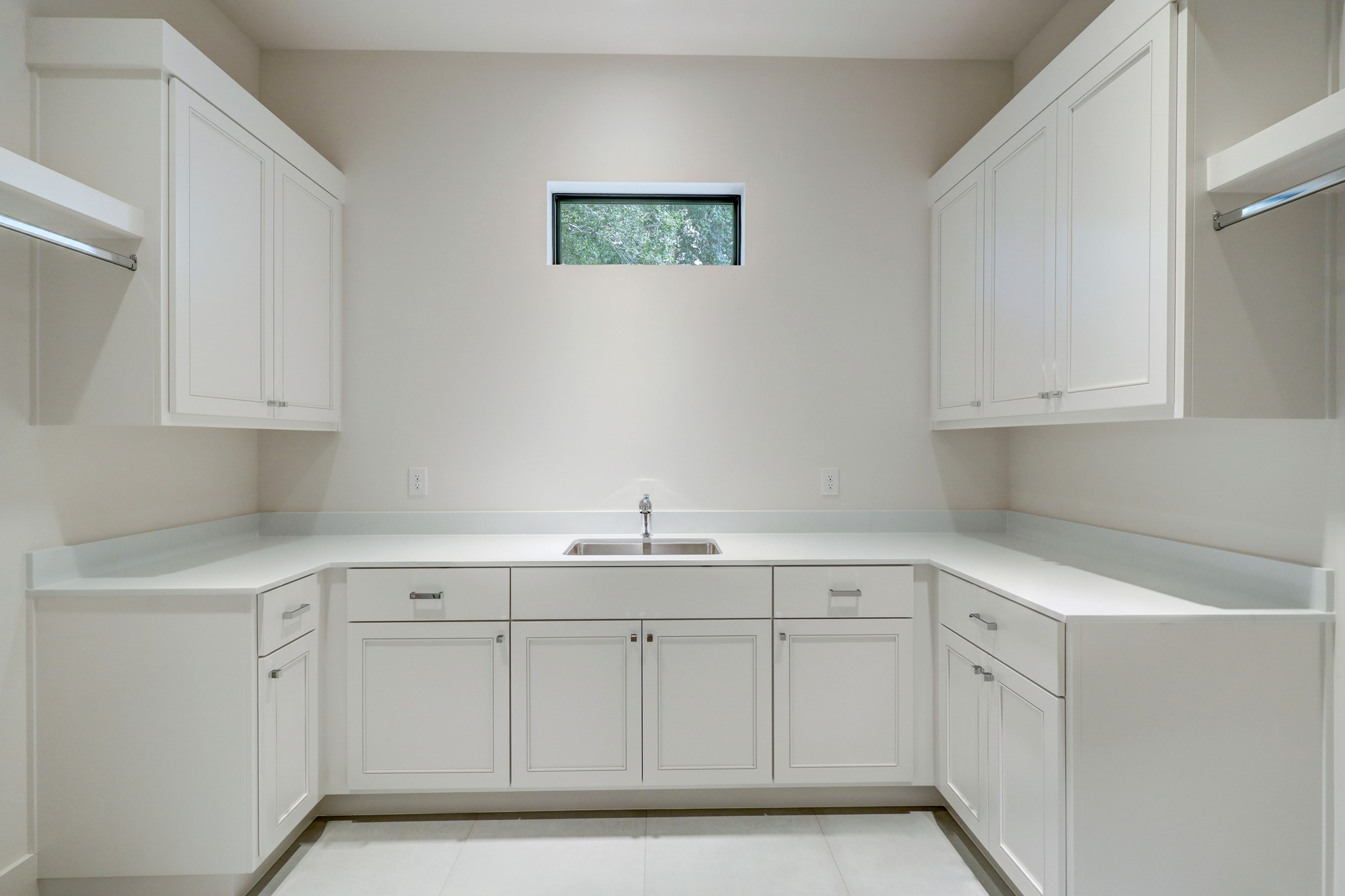 The laundry room with pocket door entrance is on the first floor off the mud room. It features a sink, ample counter space, two hanging rods, and built-in storage.