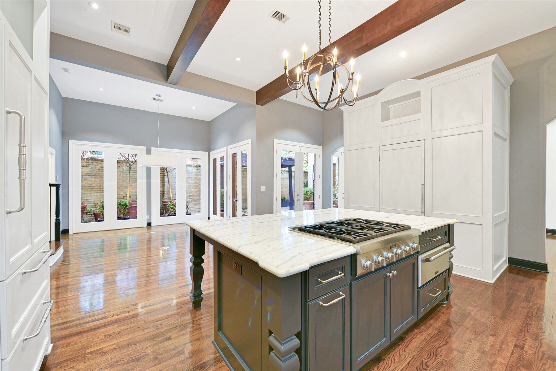 Beamed 12 foot ceilings and designer pendant light elevate the kitchen space, accent the custom cabinets, and large​​‌​​​​‌​​‌‌​‌‌​​​‌‌​‌​‌​‌​​​‌​​ island.