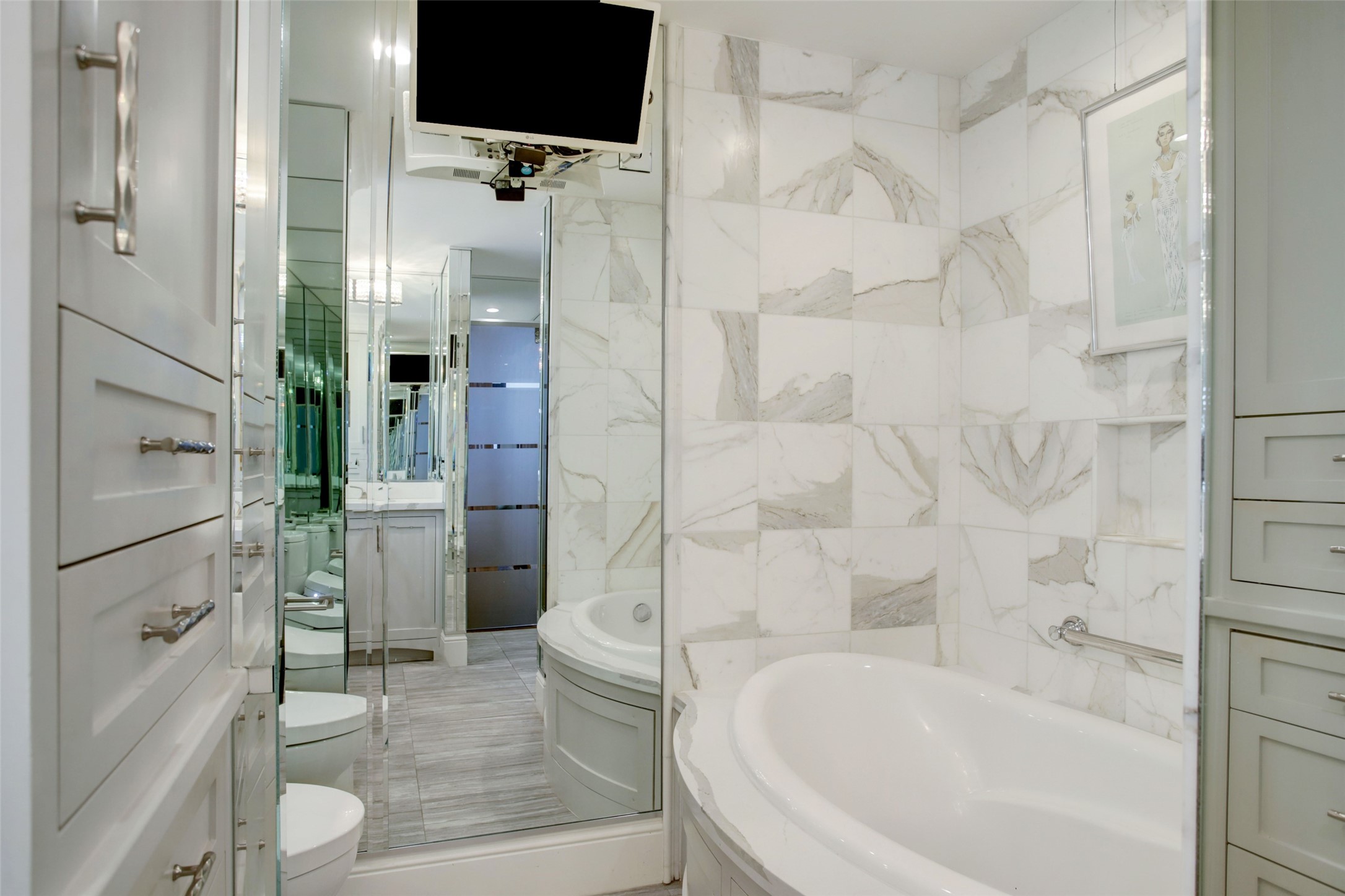 The primary ensuite is equipped with an airjet tub with marble tile surround, Toto Washlet toilet and more custom built-ins.