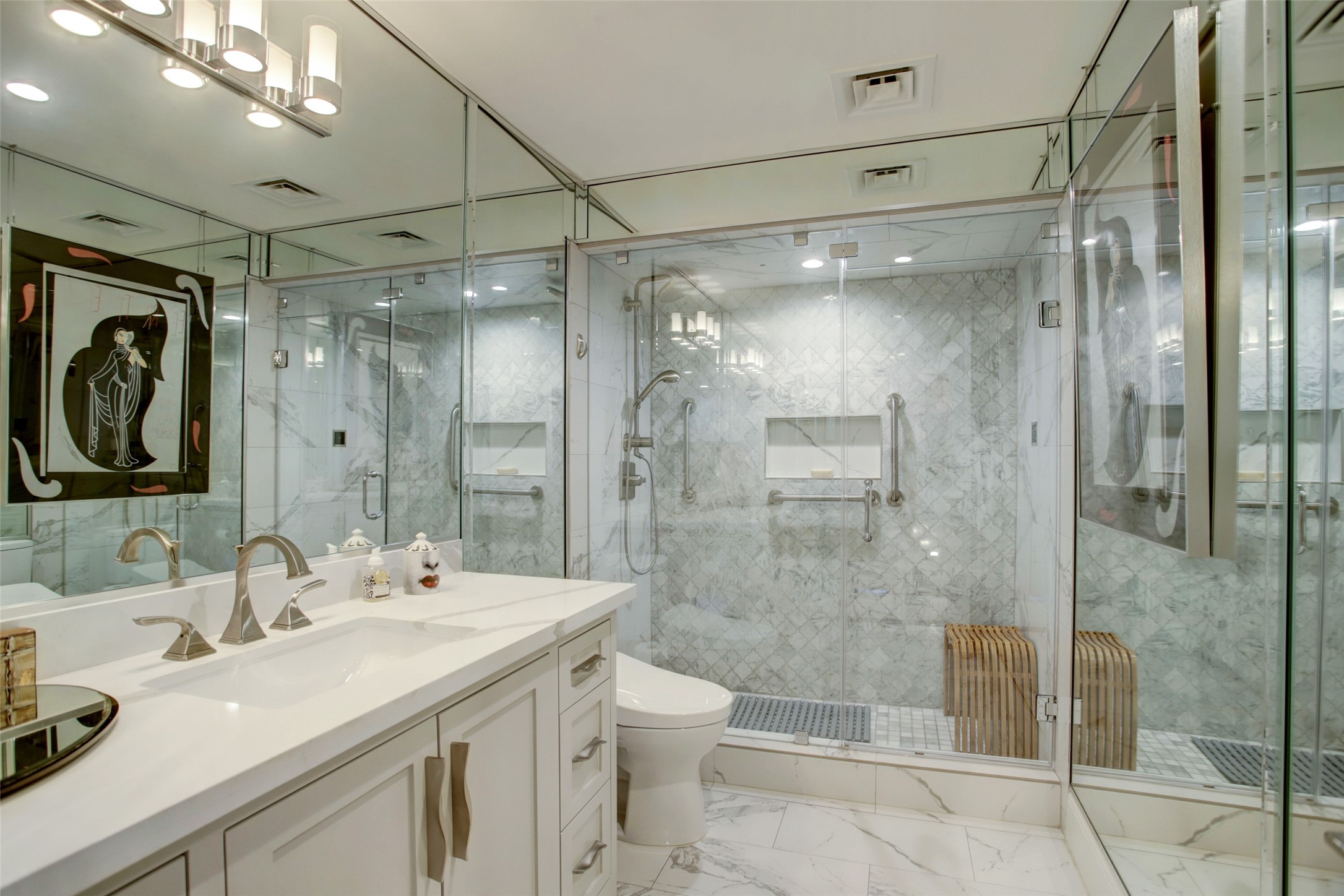 The hallway guest bathroom is another beauty, with an elegant marble tiled steam shower, Toto Washlet toilet, accent lighting and a full mirrored wall.