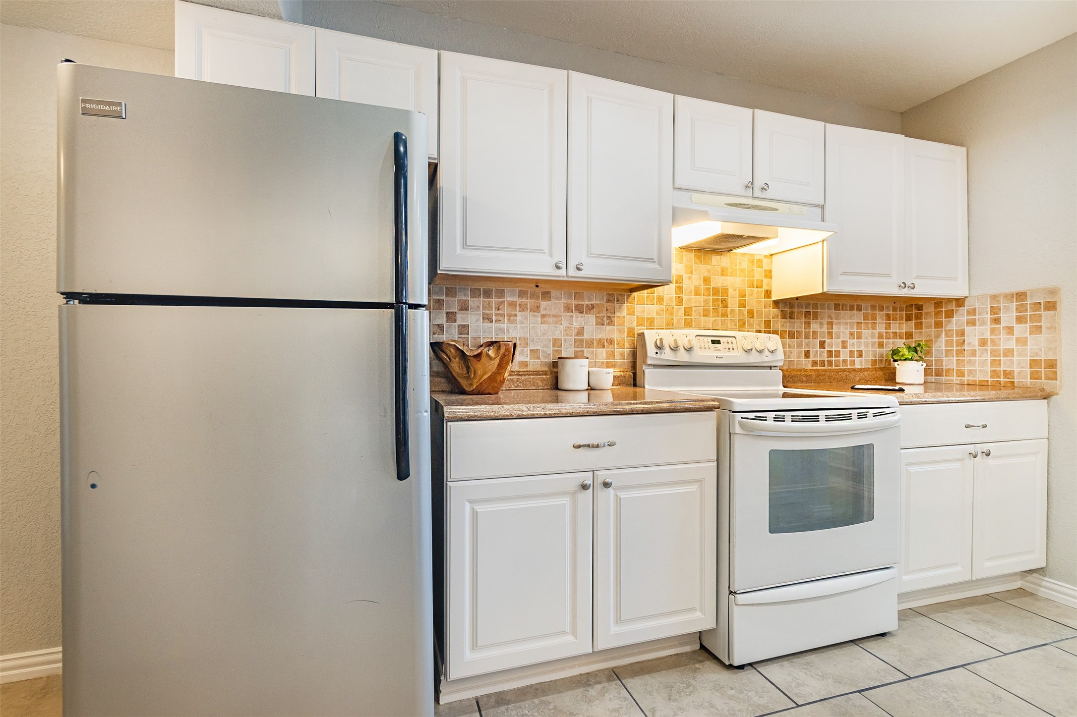 The kitchen features modern white cabinets and tile backsplash.