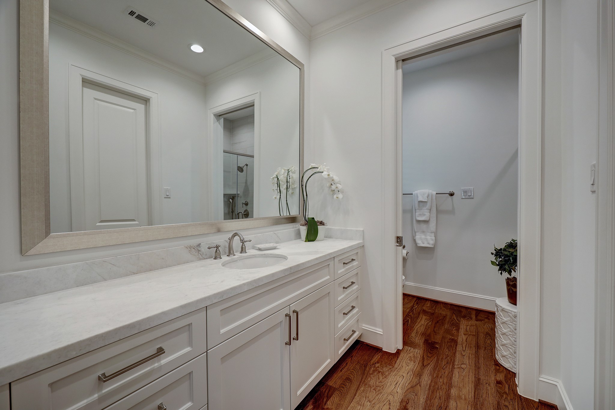 The ensuite guest bathroom features an oversized honed marble counter, large walk-in closet with custom shelving, dual head walk-in shower with seat and hand mount shower head.