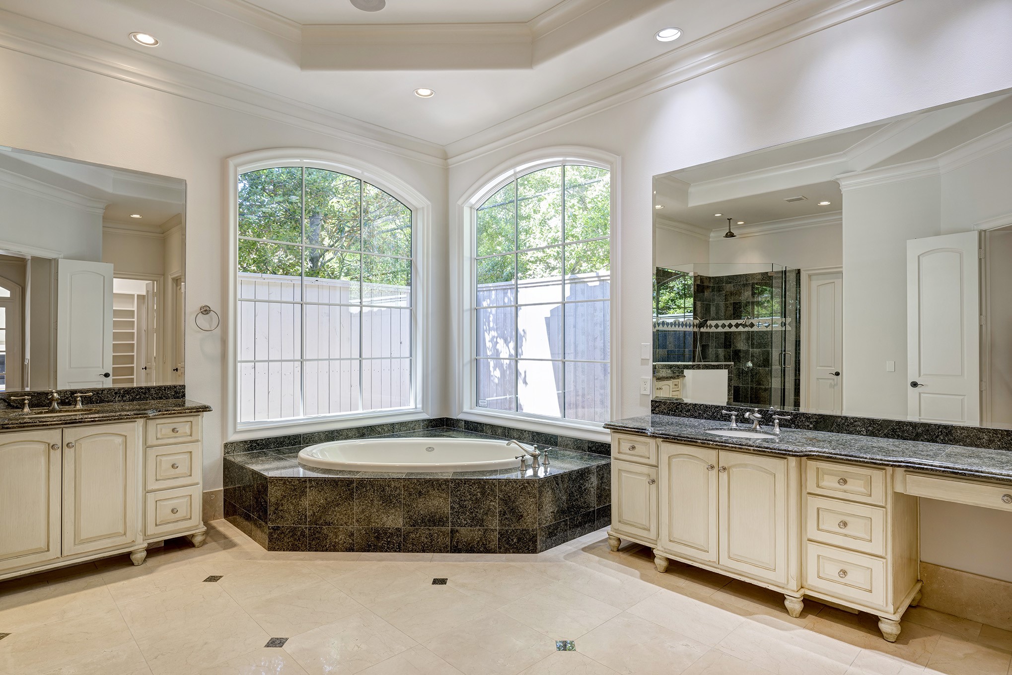 Primary bath with double vanities, soaking tub, separate glass shower and two walk-in closets.