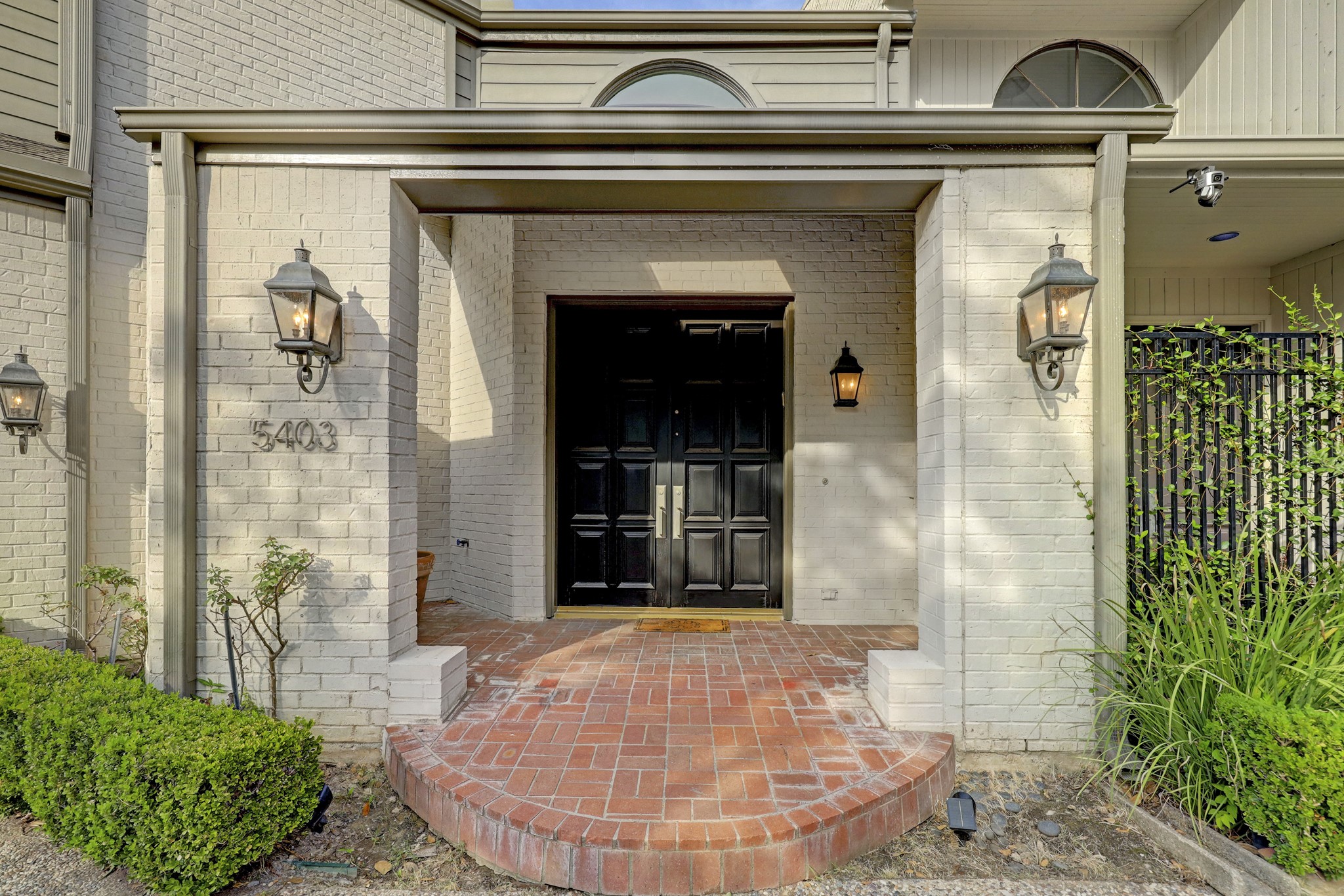 Welcoming curb appeal with a brick landing, light sconces, and a double front entry door.