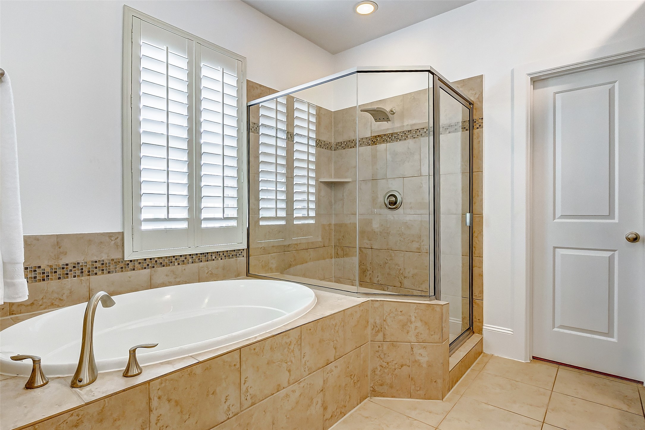 Your new primary ensuite offers a garden tub and separate stand-up glass shower with matching tub and shower surround, brushed nickel fixtures, and shower lighting.