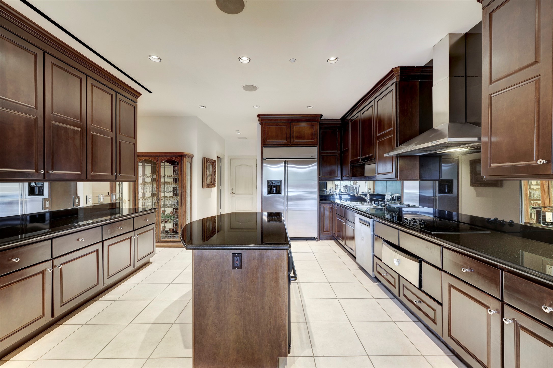Huge island kitchen with granite counters and a mirrored backsplash.