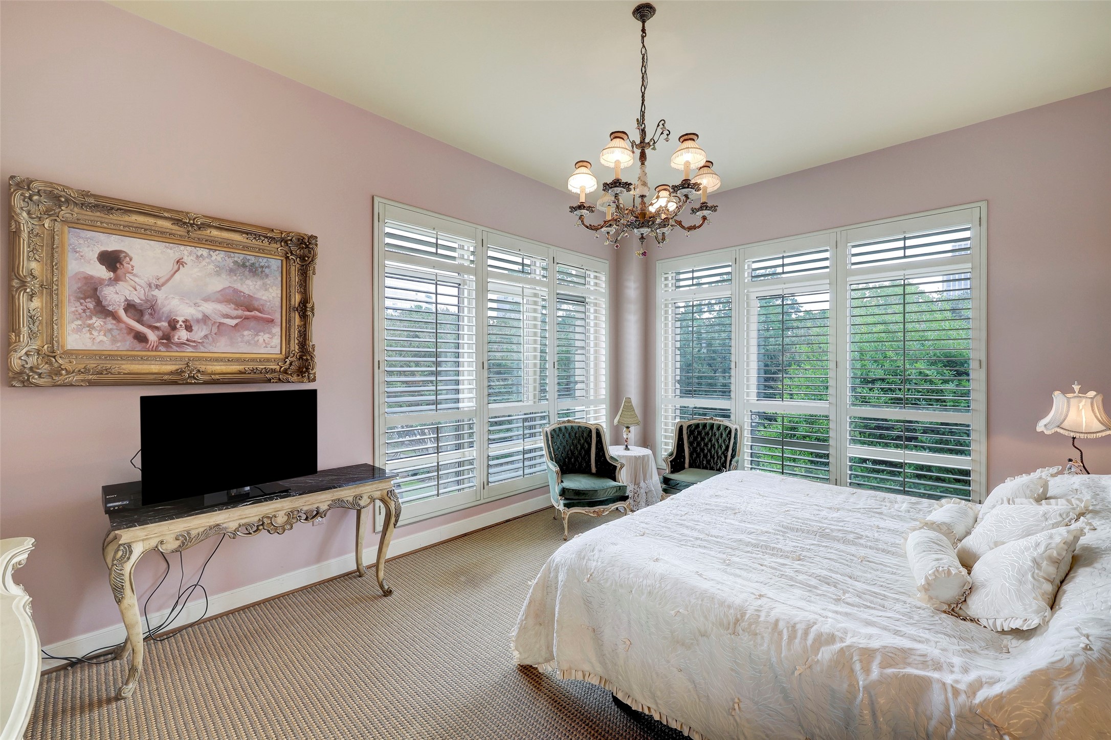Lovely primary room with corner treetop views, plantation shutters and solar shades.