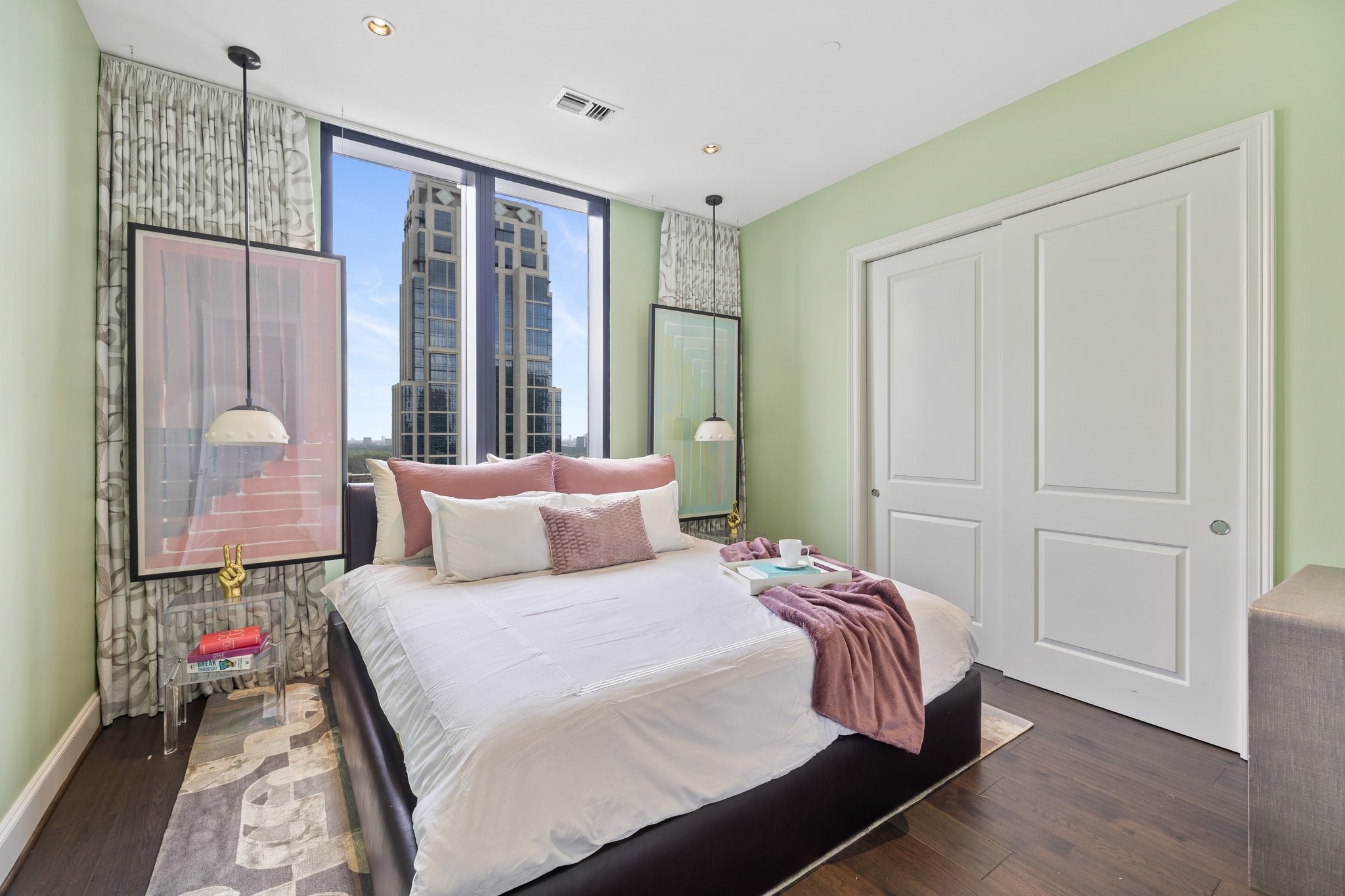 A bedroom with expansive city views through the large windows, complemented by artistic decor elements.