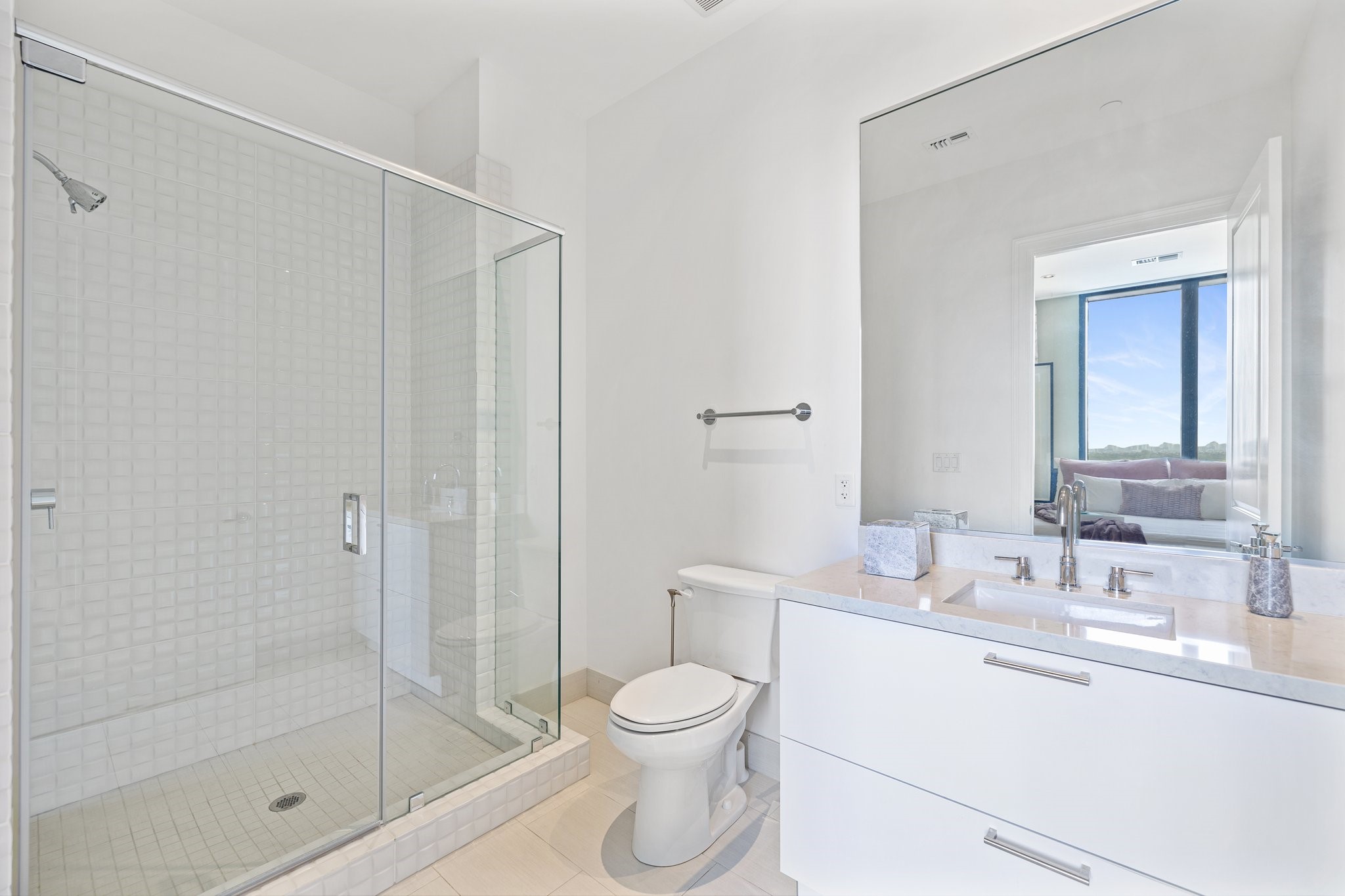 An ensuite attached to a secondary bedroom, featuring a spacious and luxurious stand-up shower with meticulous tile detailing and contemporary fixtures. The room radiates with clean lines and a harmonious design.